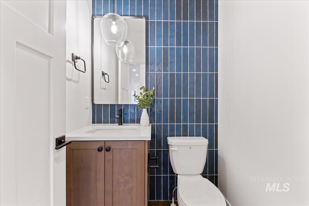 Half bathroom featuring tile walls, vanity, and decorative backsplash