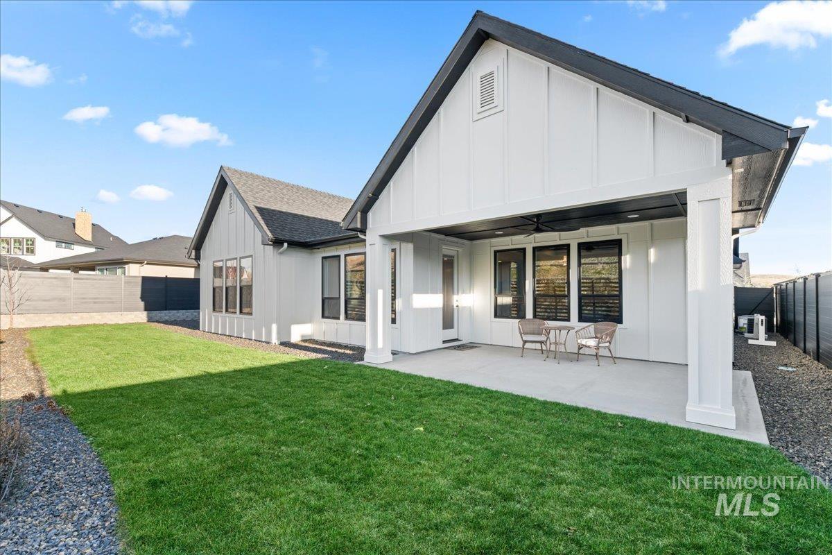 Rear view of property with board and batten siding, a ceiling fan, a fenced backyard, and a patio