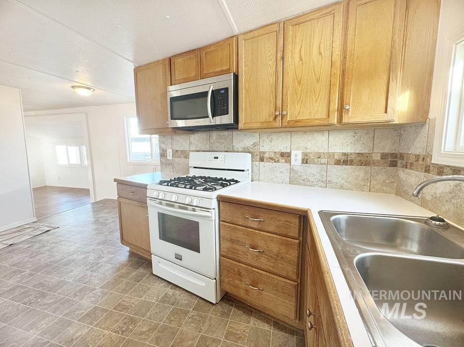 Kitchen featuring white gas range, healthy amount of natural light, stainless steel microwave, and light countertops