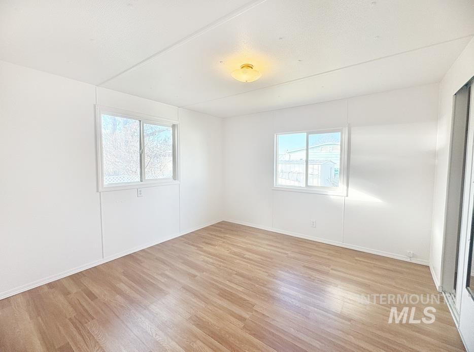 Empty room featuring light wood finished floors and healthy amount of natural light