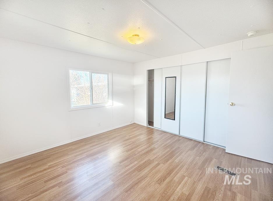 Unfurnished bedroom featuring light wood-style flooring, a closet, and a textured ceiling