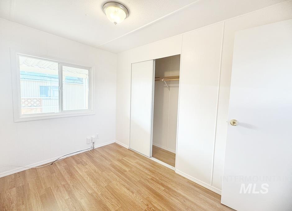 Unfurnished bedroom with light wood-type flooring and a closet