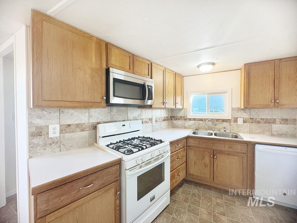Kitchen with white appliances, light countertops, and tasteful backsplash