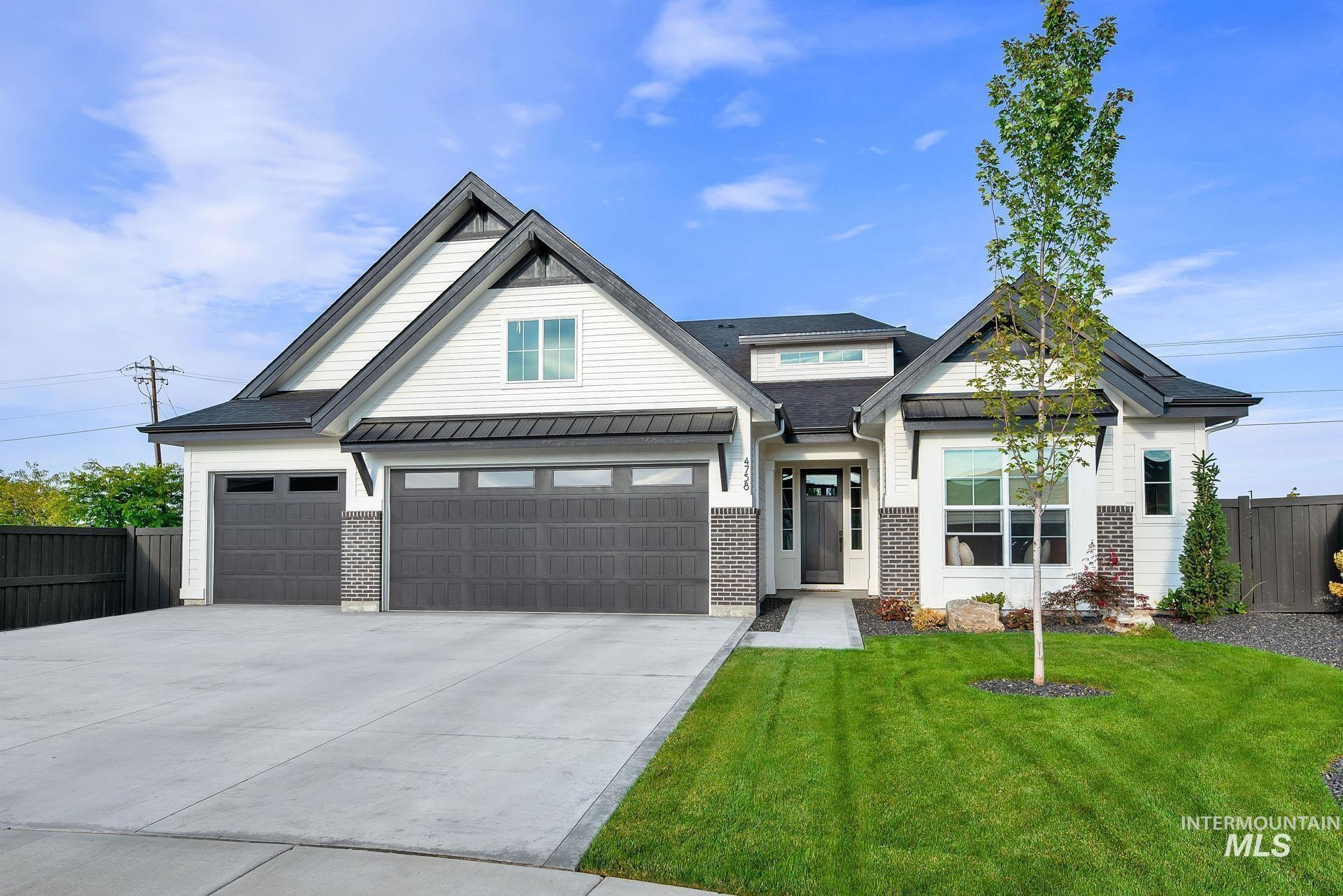 Modern farmhouse featuring a standing seam roof, concrete driveway, brick siding, a metal roof, and an attached garage