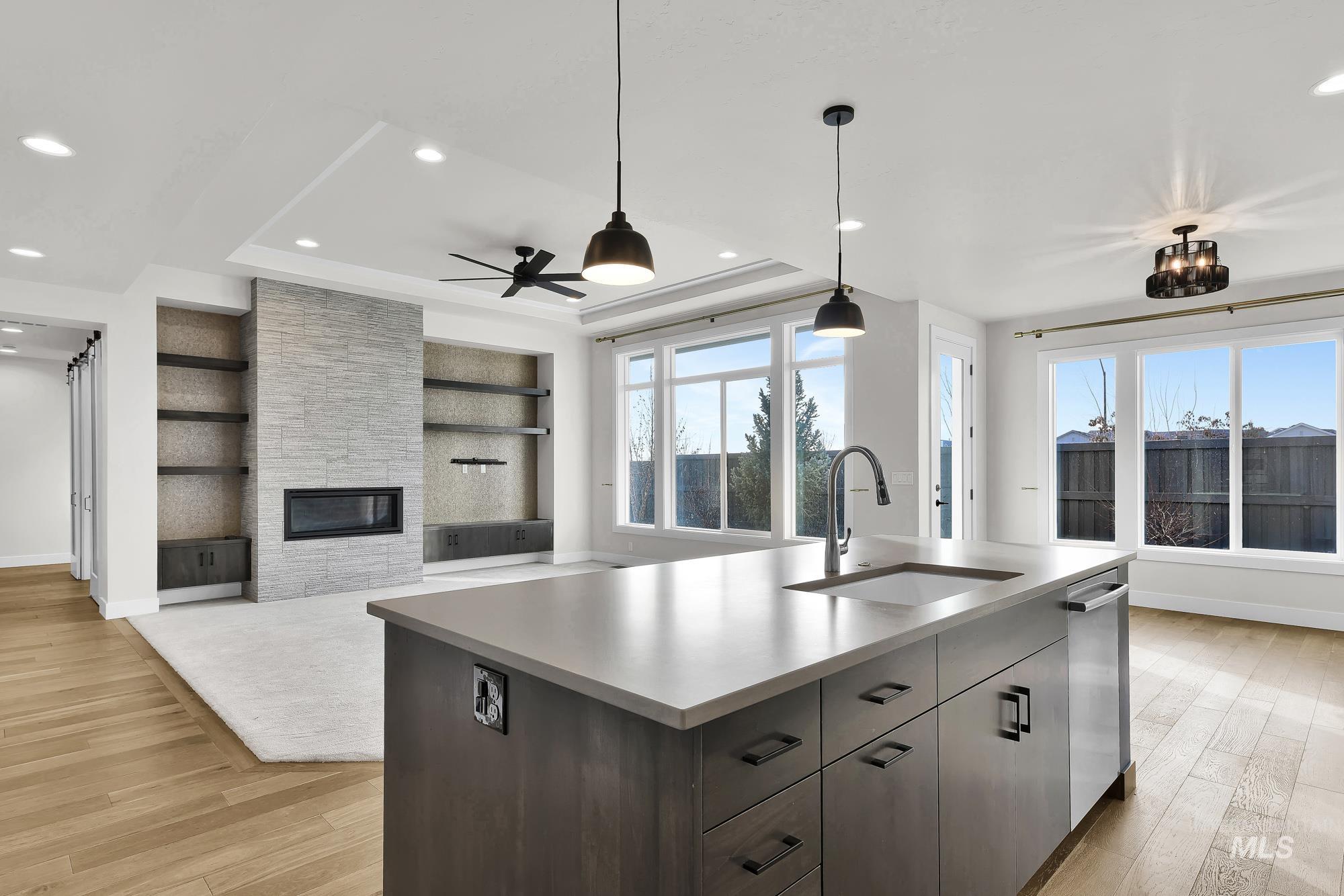 Kitchen with built in shelves, open floor plan, pendant lighting, a center island with sink, and a fireplace