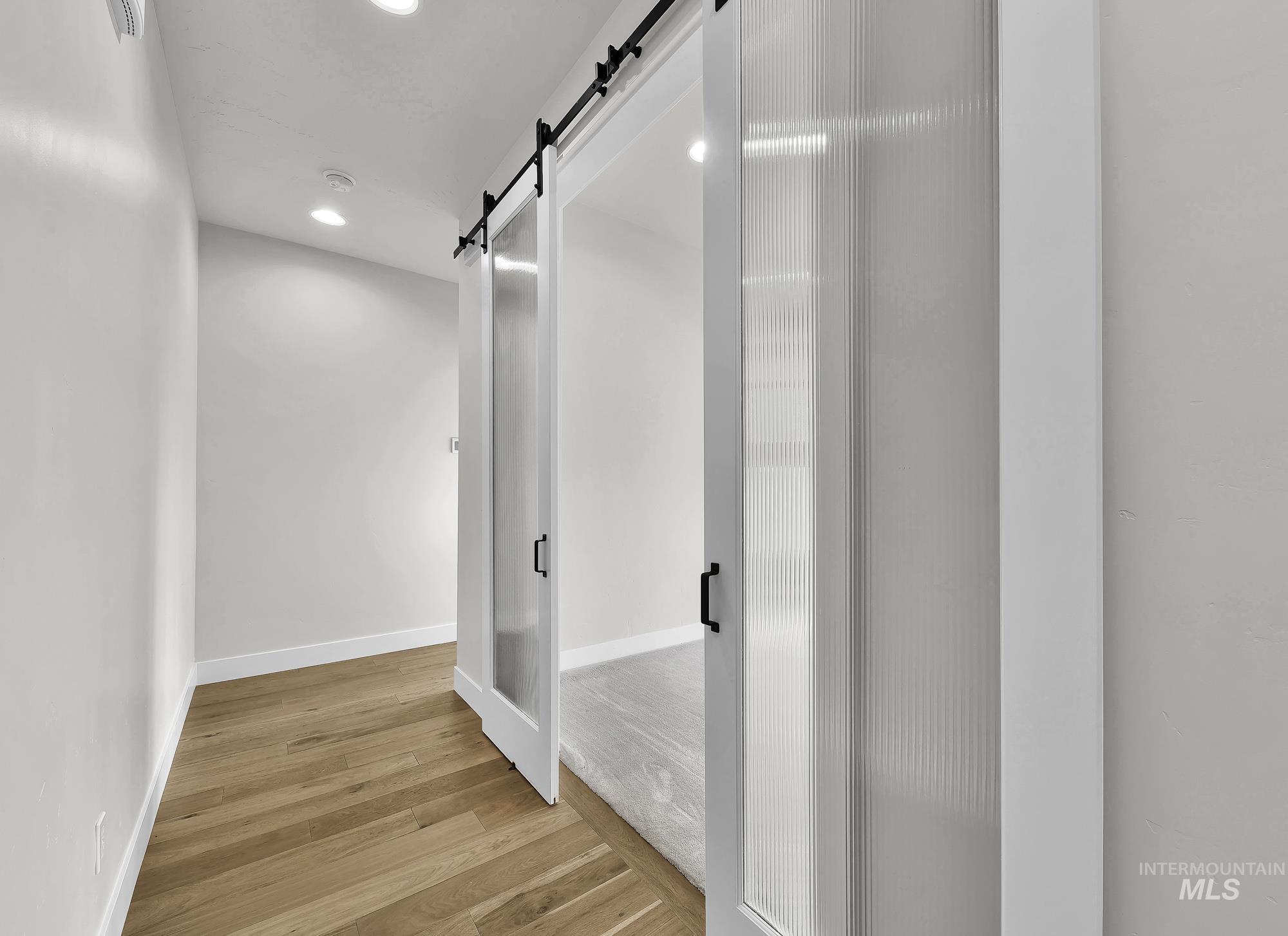 Bathroom with light wood-style floors, recessed lighting, and a shower stall