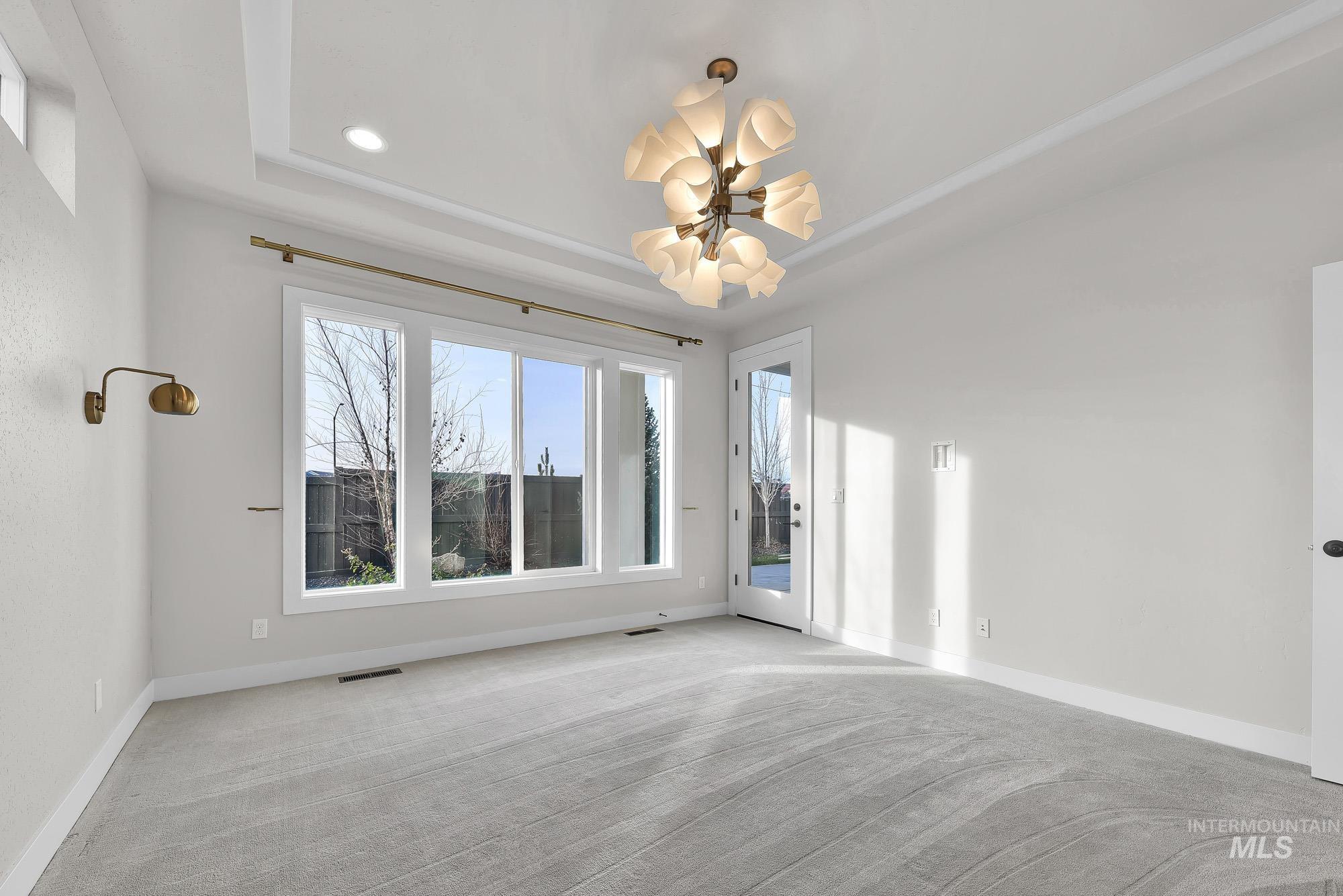 Empty room with a tray ceiling, light colored carpet, and recessed lighting