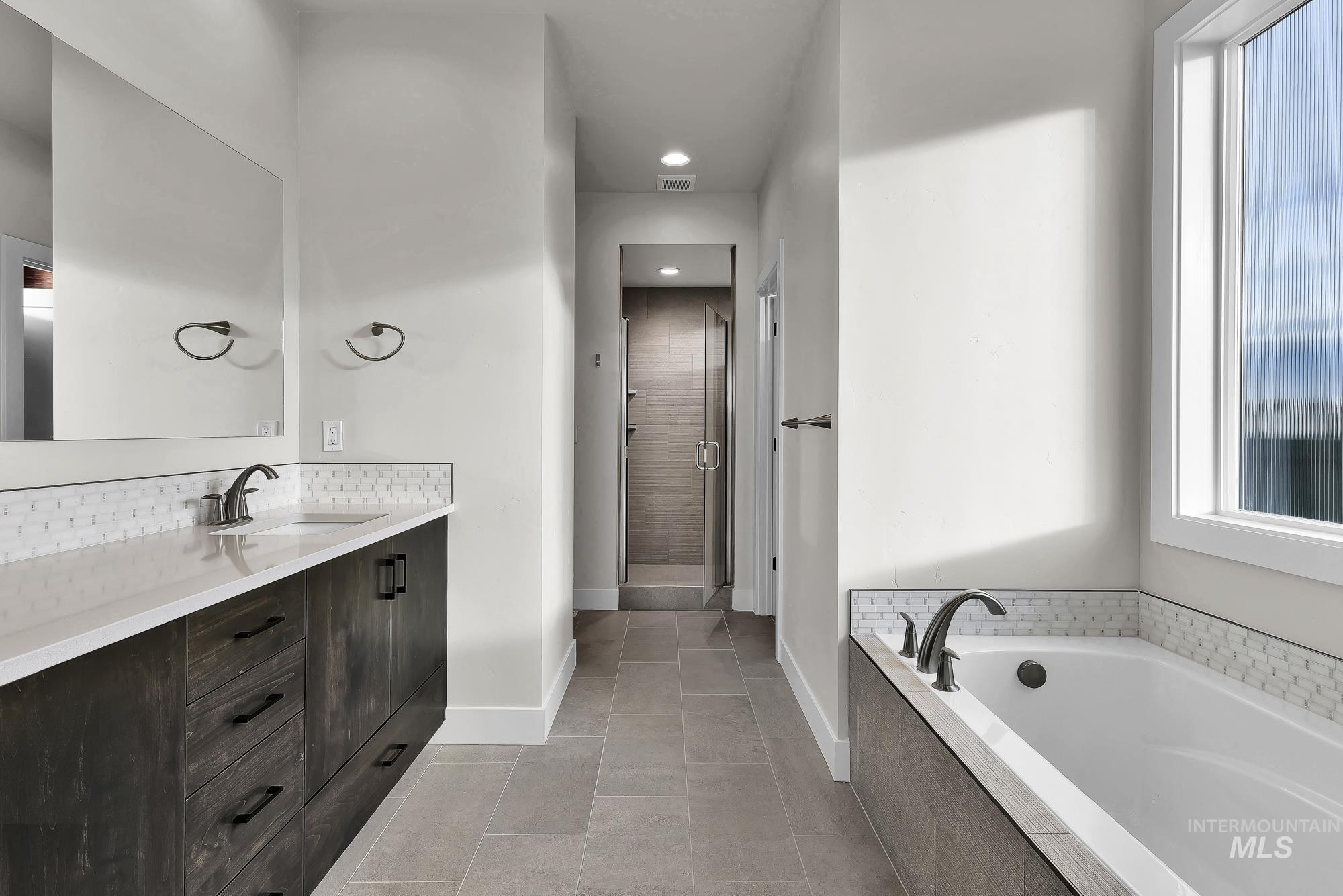 Bathroom with plenty of natural light, vanity, a shower stall, a bath, and recessed lighting