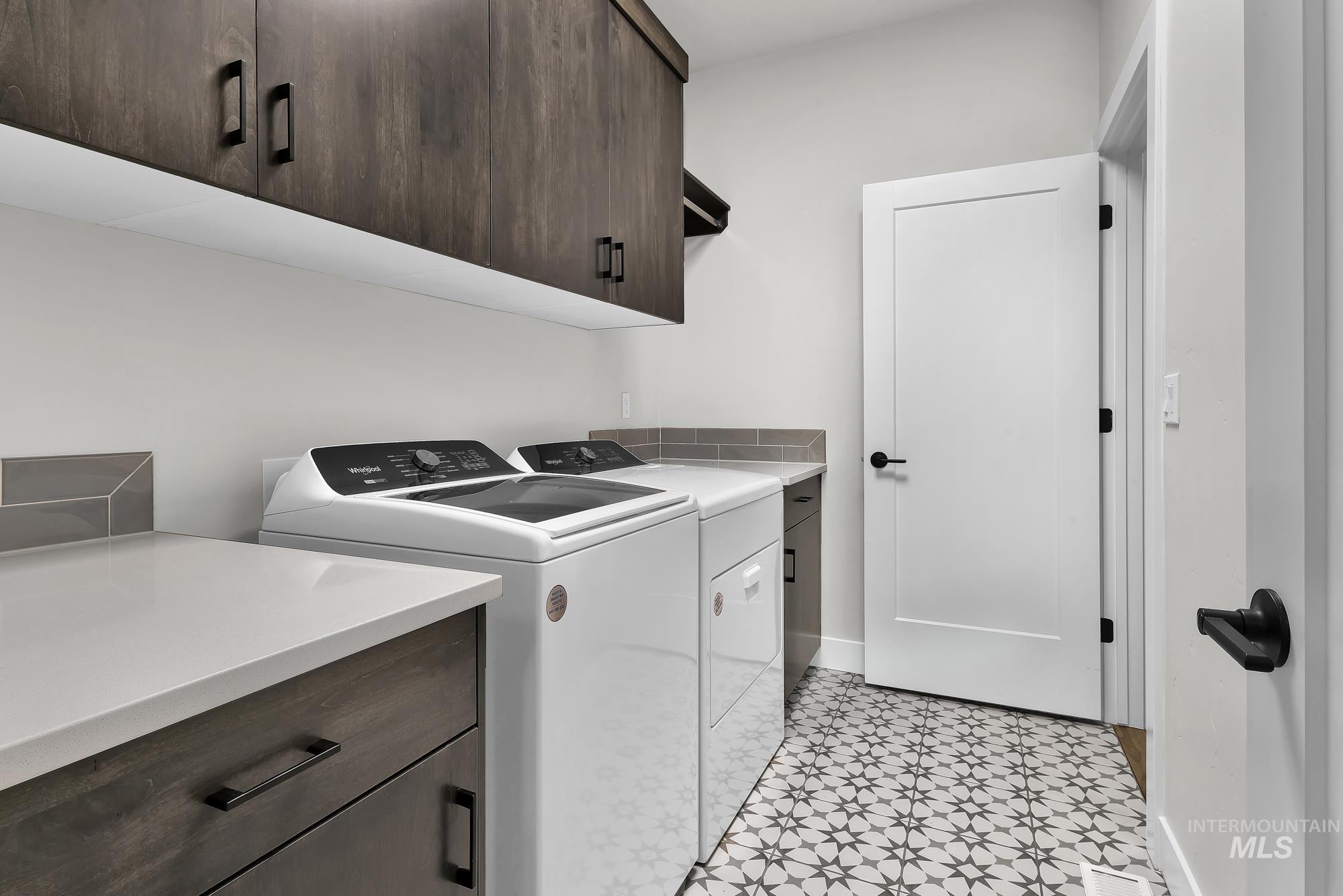 Laundry area with cabinet space, washing machine and clothes dryer, and light floors