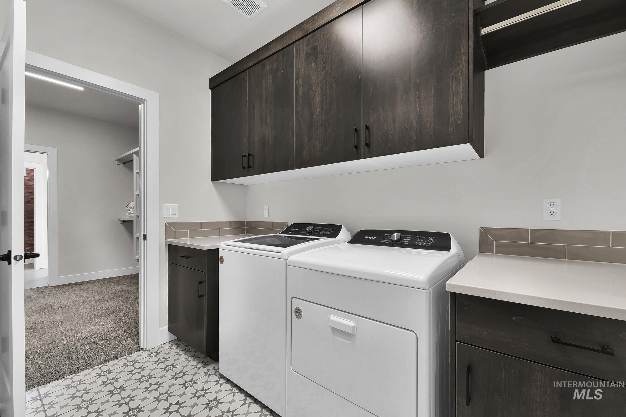 Laundry room featuring light carpet, washing machine and clothes dryer, and light floors
