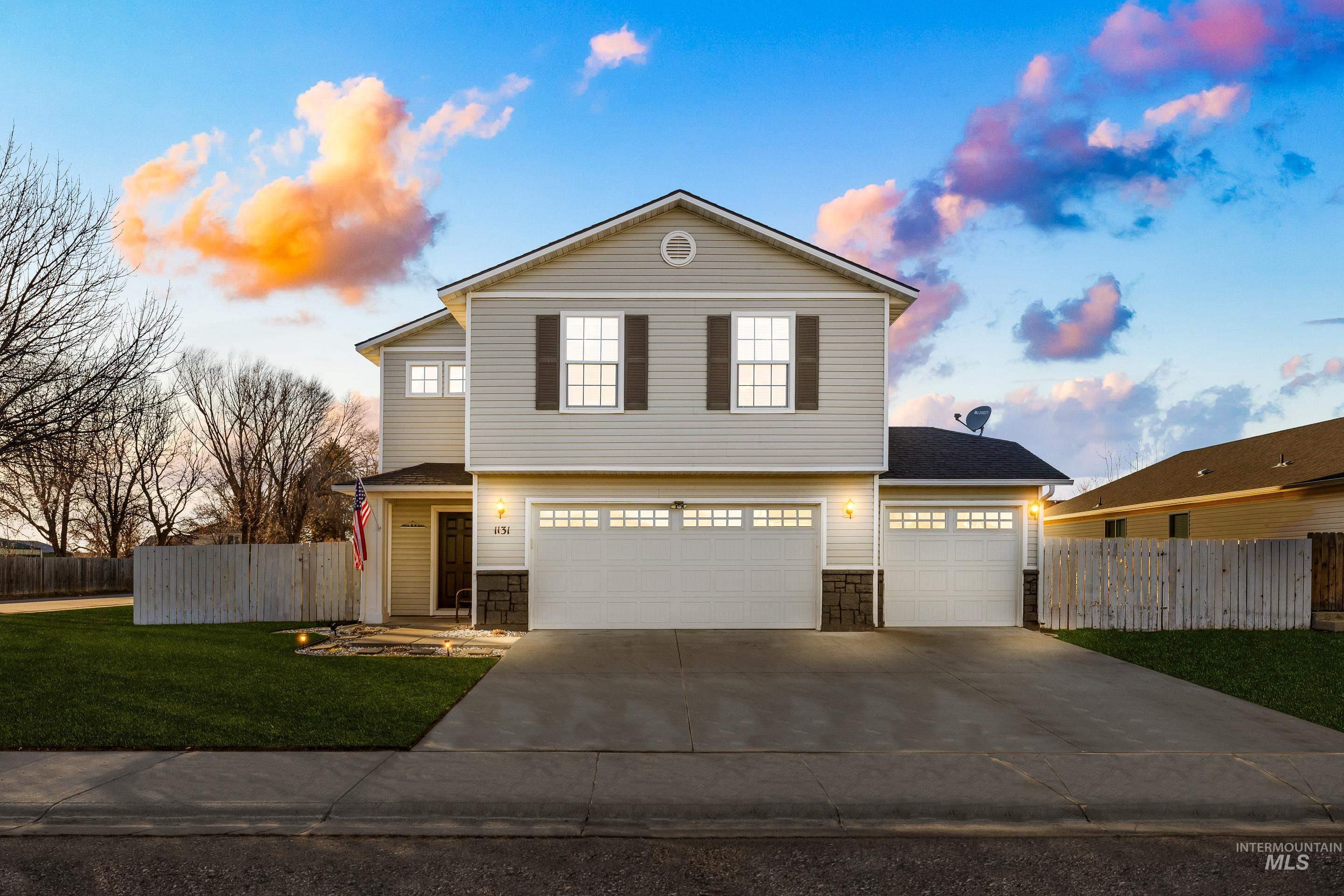 View of front of property featuring stone siding, driveway, and an attached garage