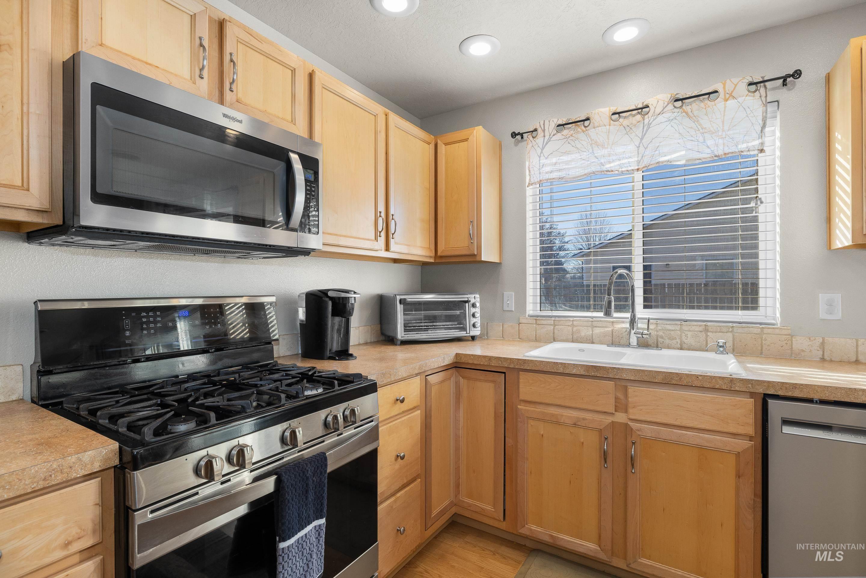 Kitchen featuring appliances with stainless steel finishes, light countertops, light brown cabinets, and recessed lighting