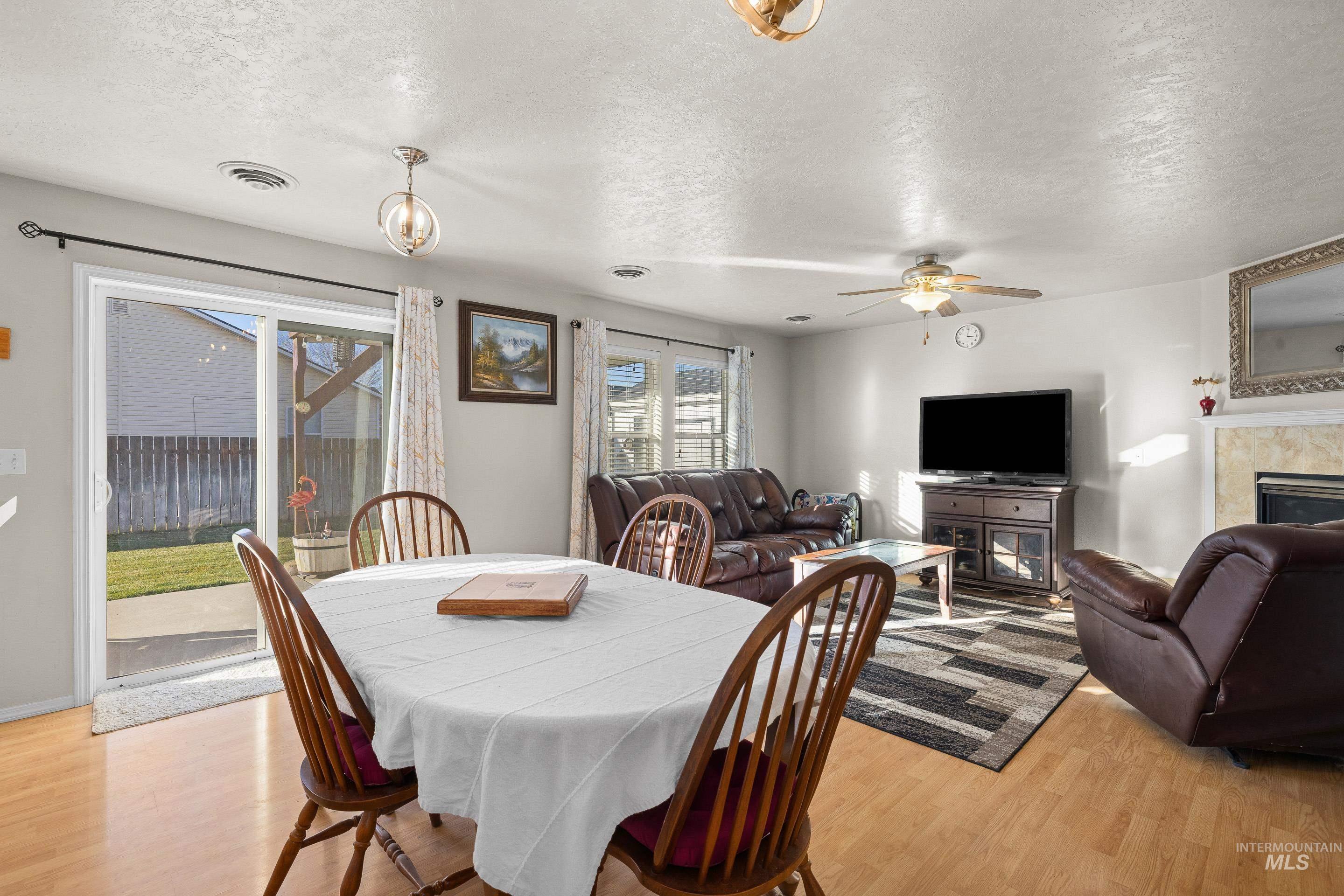Dining space featuring a textured ceiling, a fireplace, light wood-type flooring, and a ceiling fan