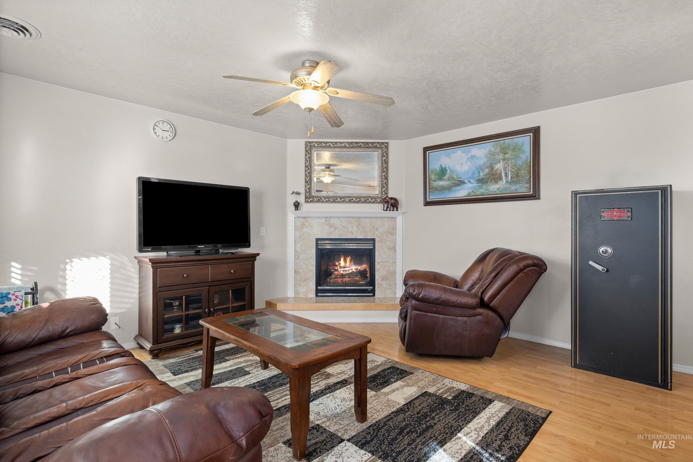 Living area featuring light wood-type flooring, a ceiling fan, and a fireplace