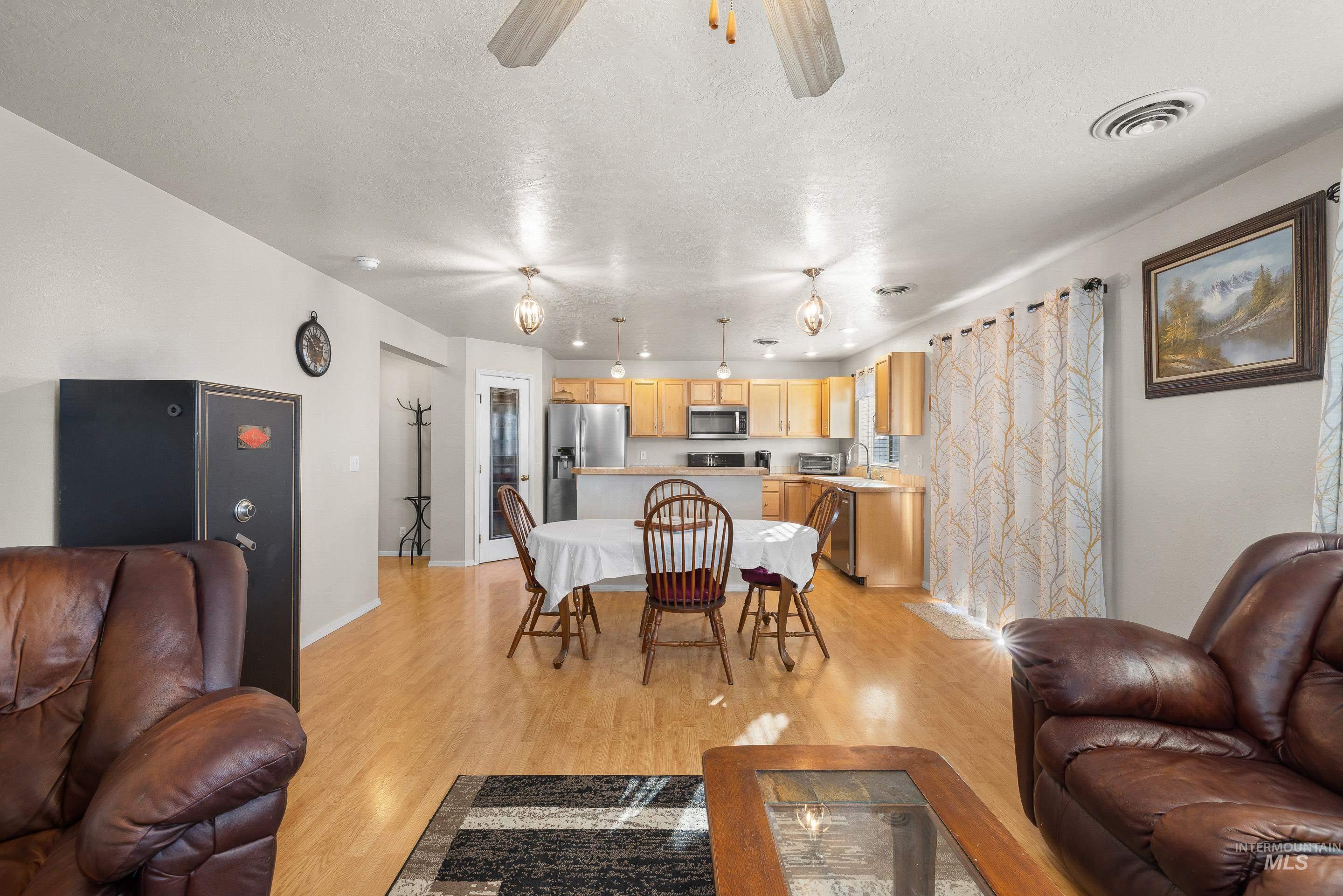 Living room with light wood-type flooring, a ceiling fan, and a textured ceiling