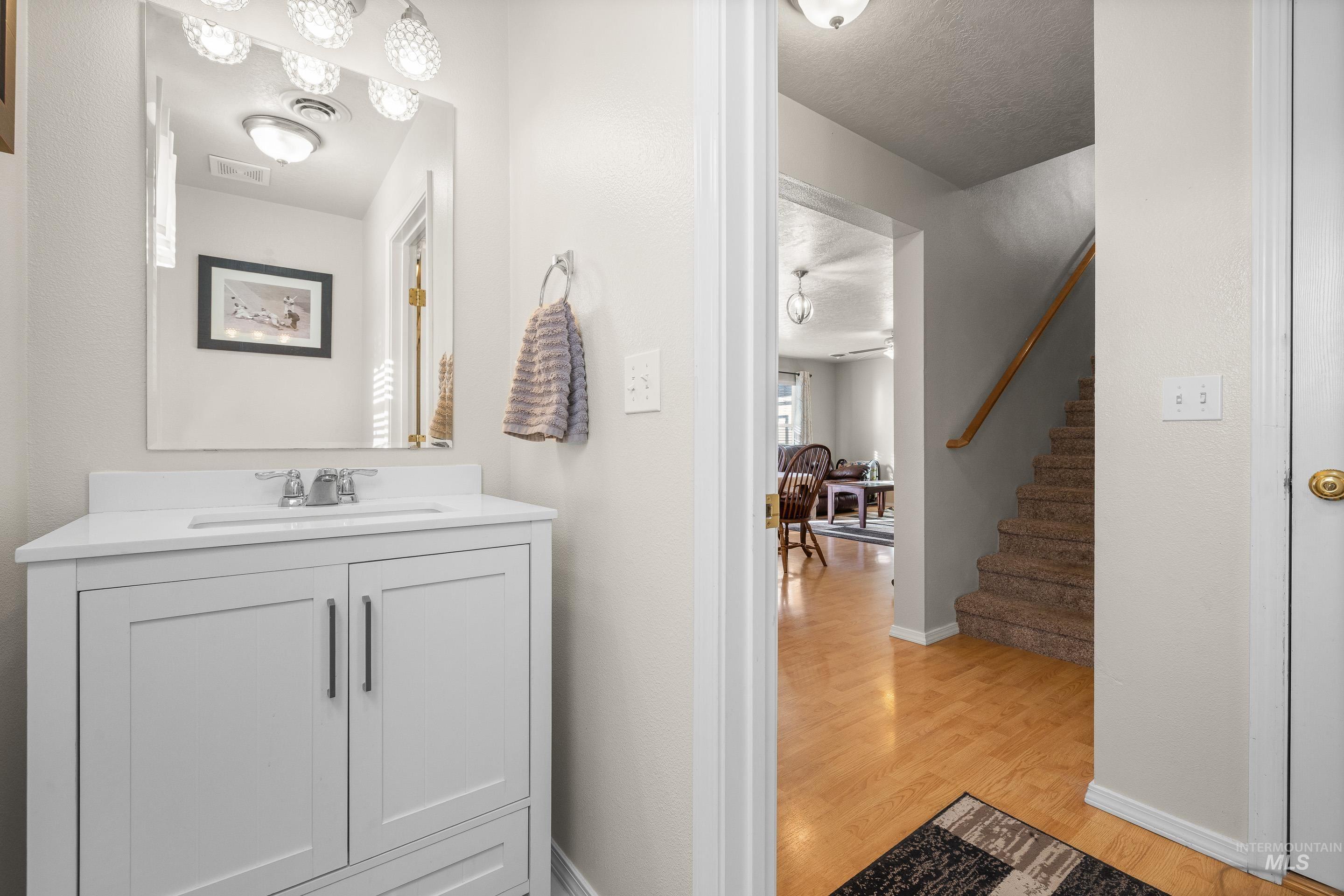 Bathroom with vanity, light wood-type flooring, and a textured ceiling