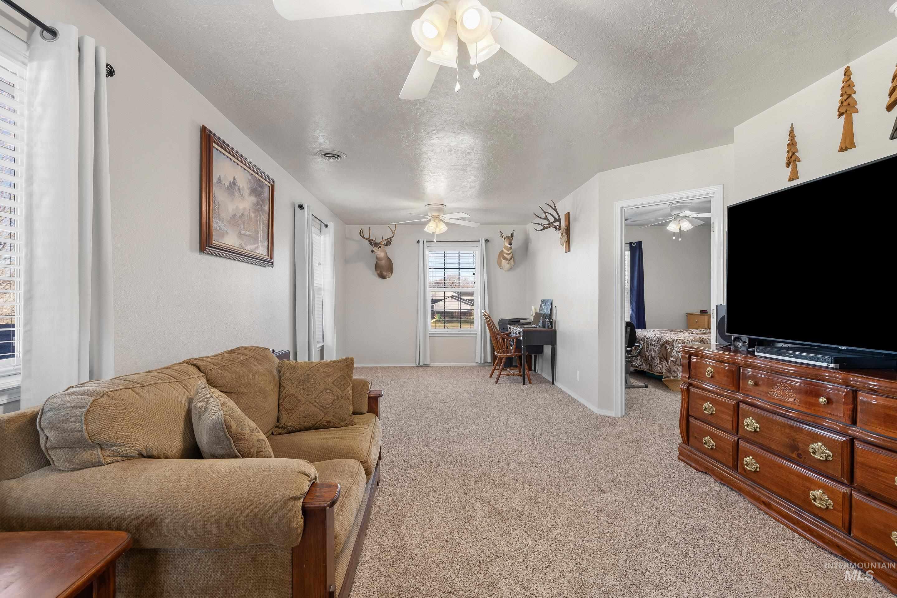 Living room featuring a desk, light carpet, and a textured ceiling