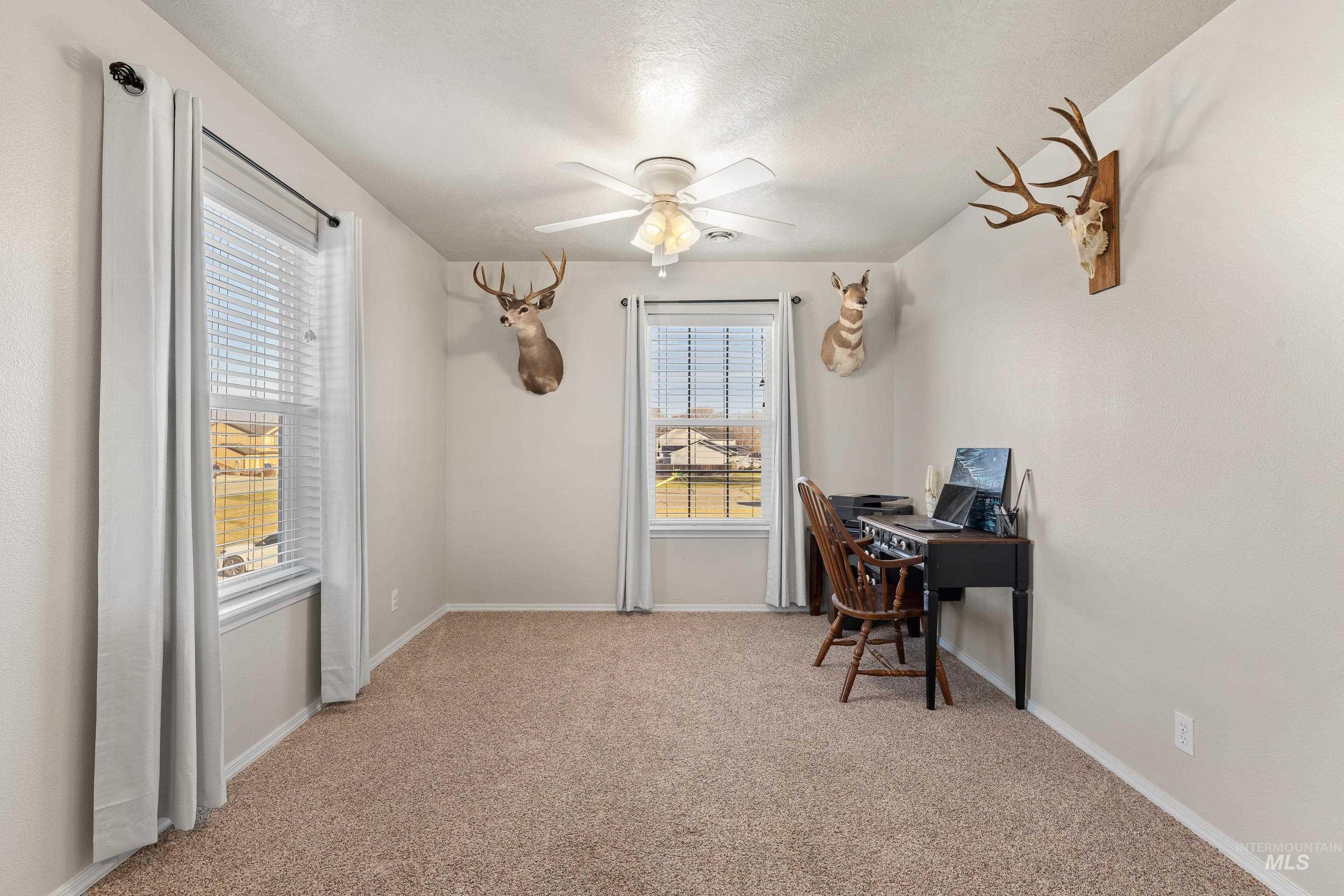 Home office featuring light colored carpet and a ceiling fan