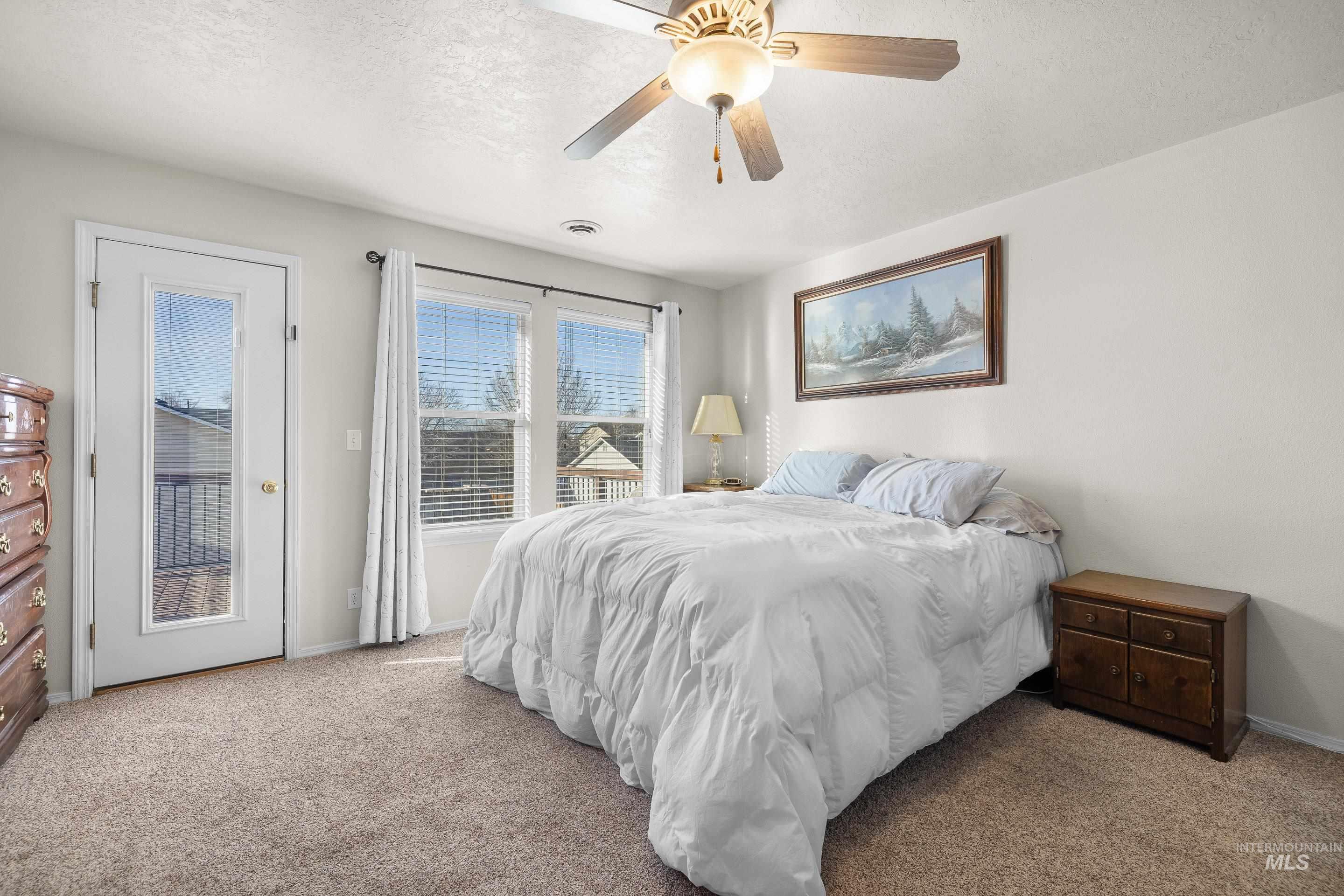 Carpeted bedroom featuring access to outside, a ceiling fan, and a textured ceiling