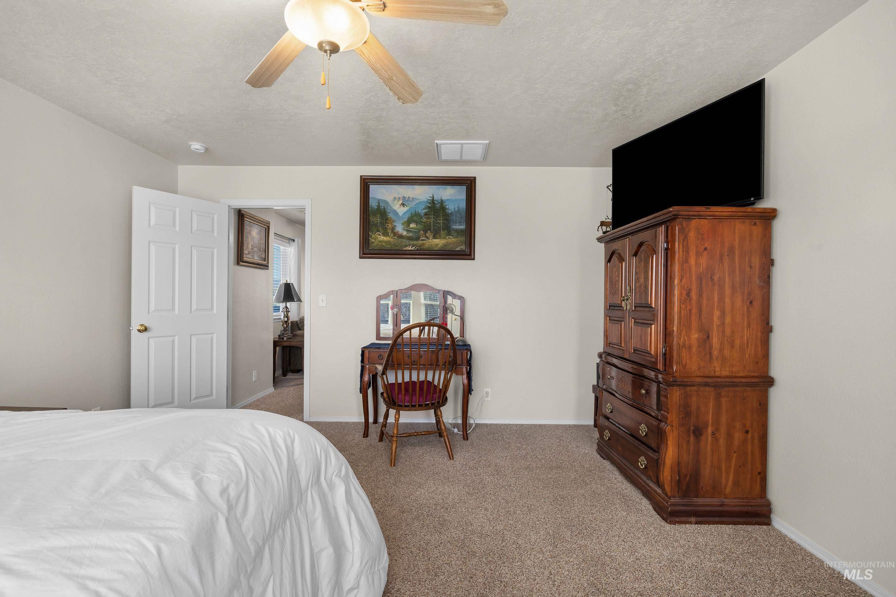 Bedroom with light colored carpet, a ceiling fan, and a textured ceiling