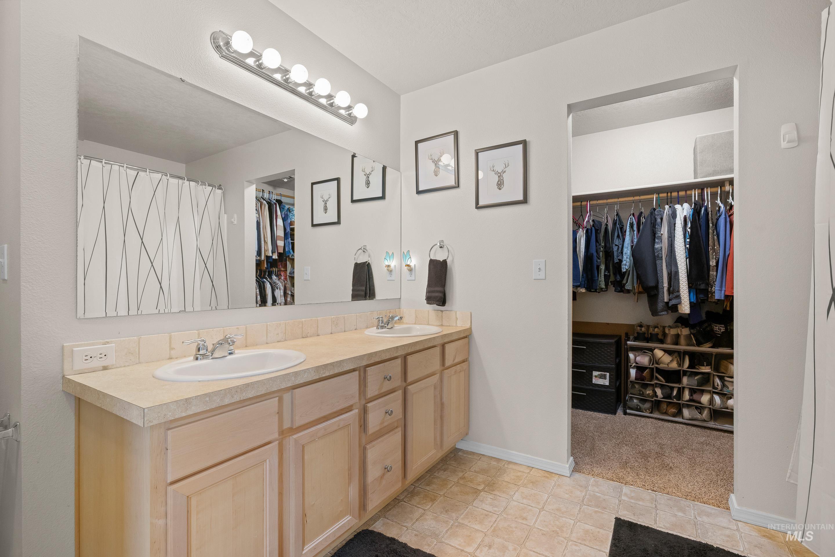 Full bathroom with a walk in closet, double vanity, curtained shower, light tile patterned floors, and light carpet