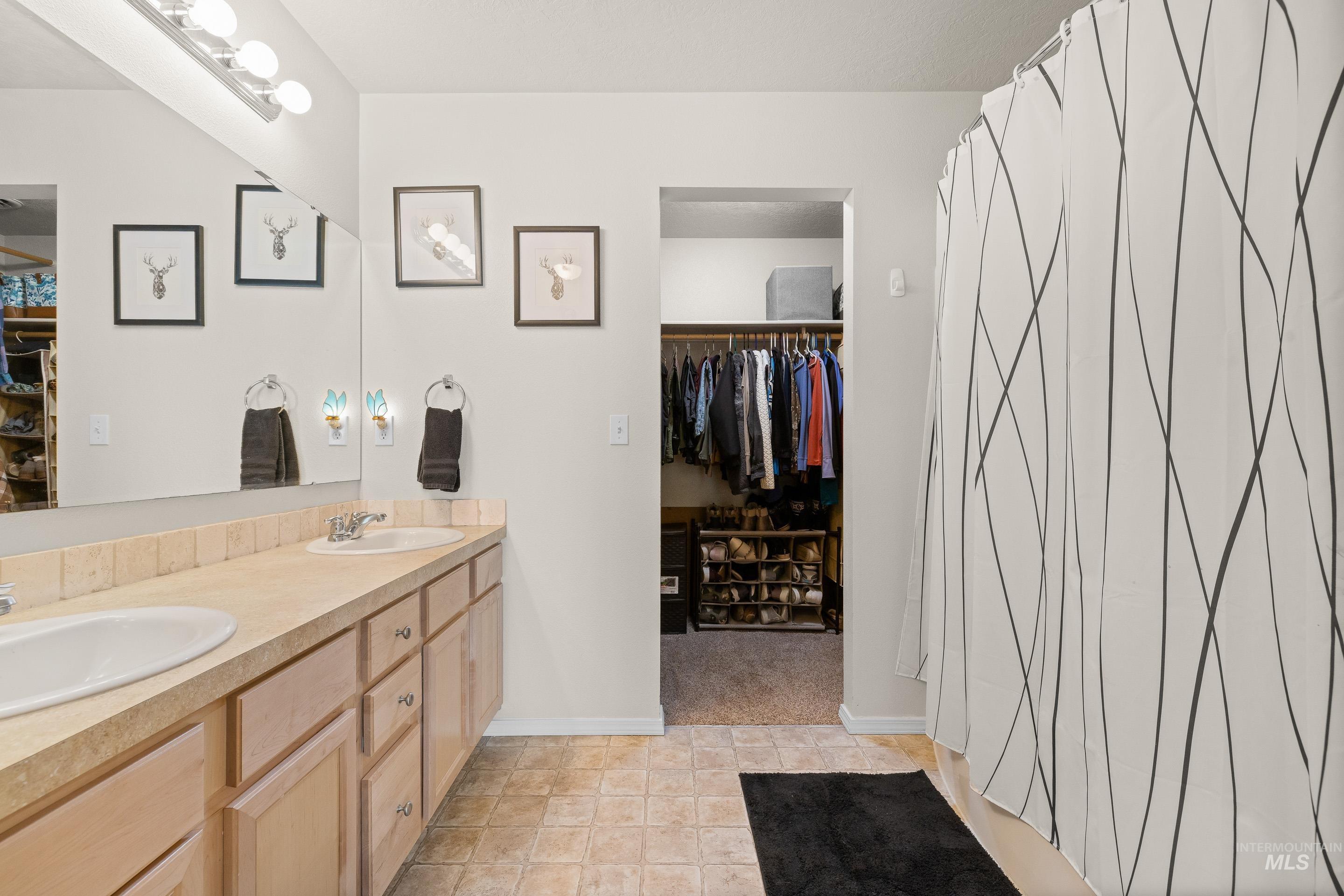Full bathroom with a walk in closet, double vanity, and curtained shower