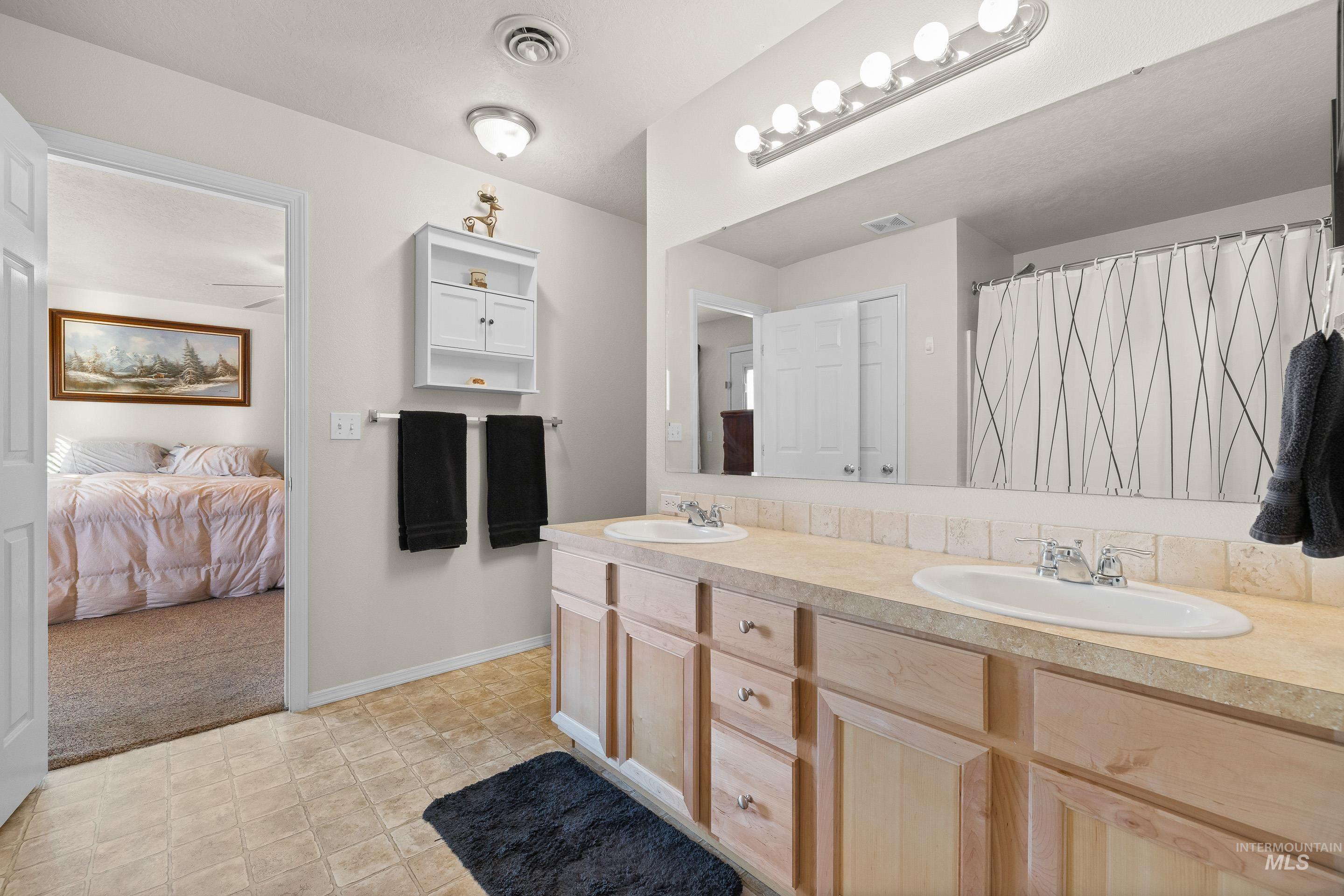 Bathroom with double vanity, a shower with shower curtain, connected bathroom, light colored carpet, and light flooring