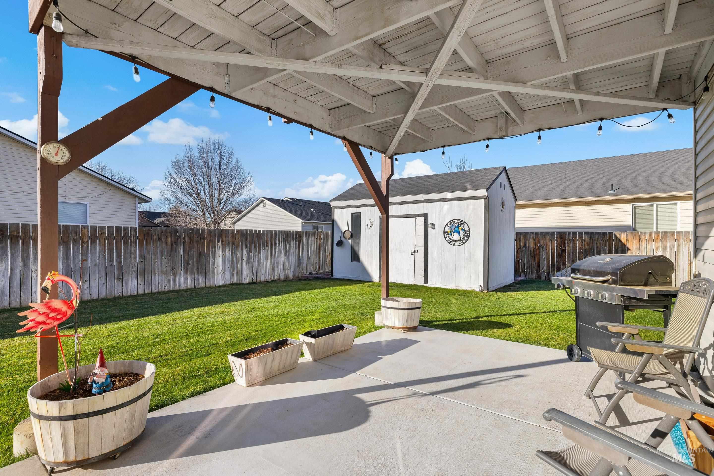 Fenced backyard with a grill, a shed, and a patio area