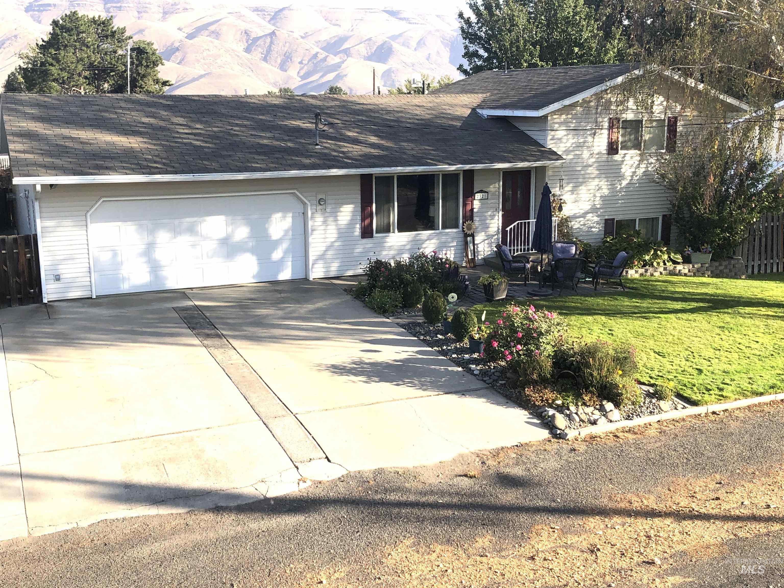 Tri-level home with driveway, a shingled roof, and a garage