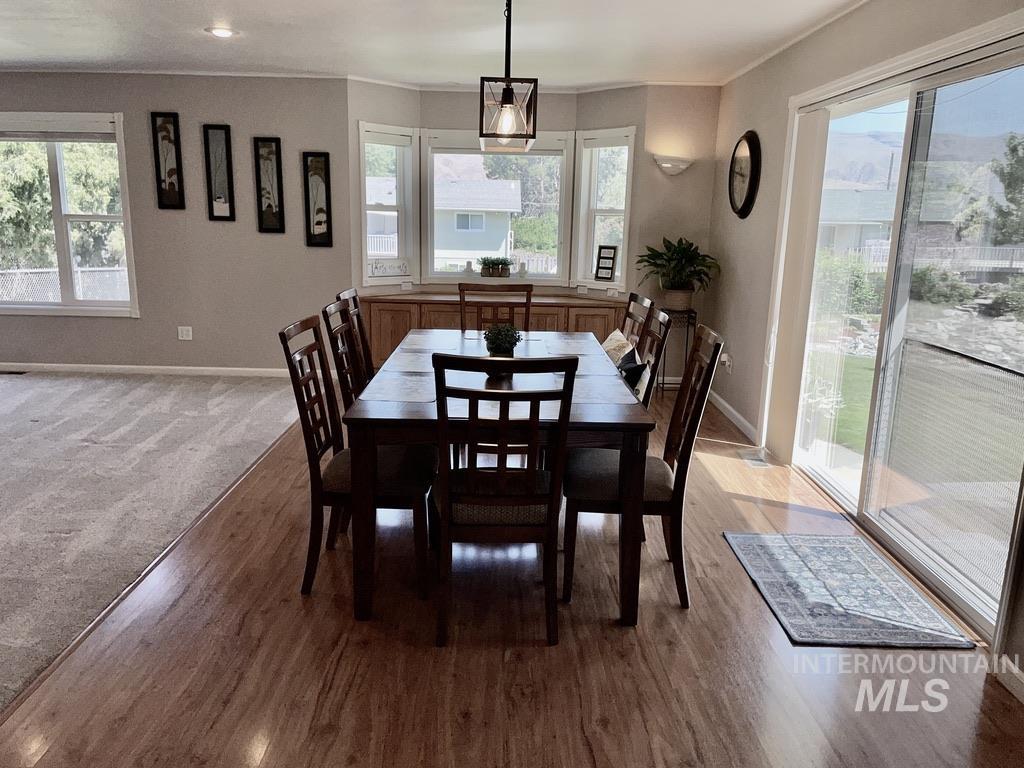 Dining area with plenty of natural light, crown molding, light wood-style floors, and light carpet