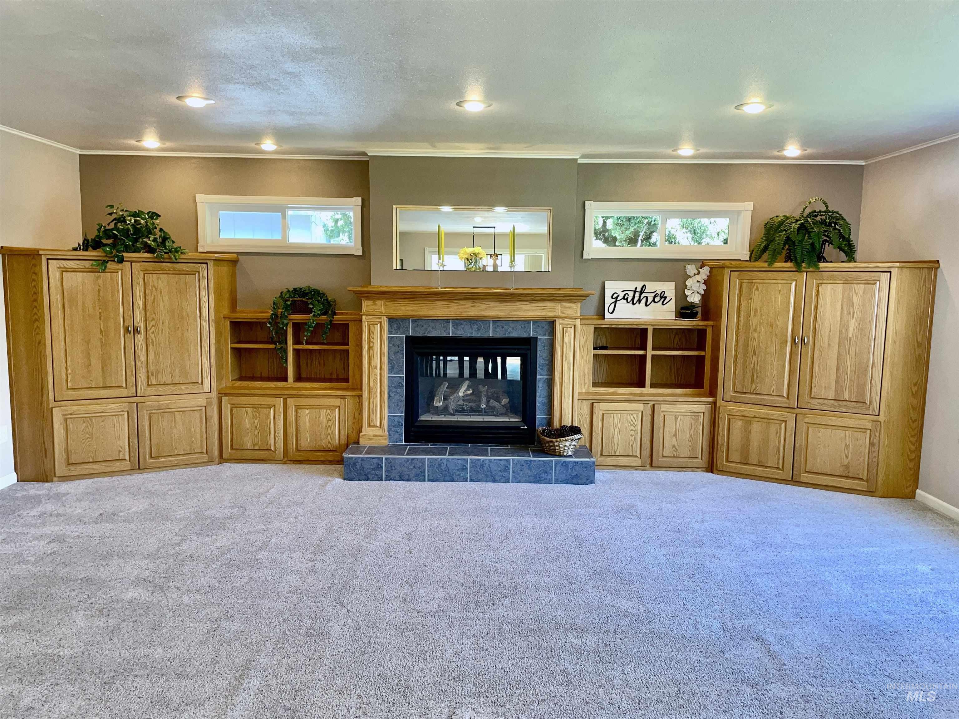 Living room featuring a tile fireplace, light colored carpet, and crown molding