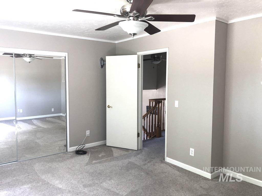 Unfurnished bedroom with ornamental molding, carpet, a ceiling fan, and a closet