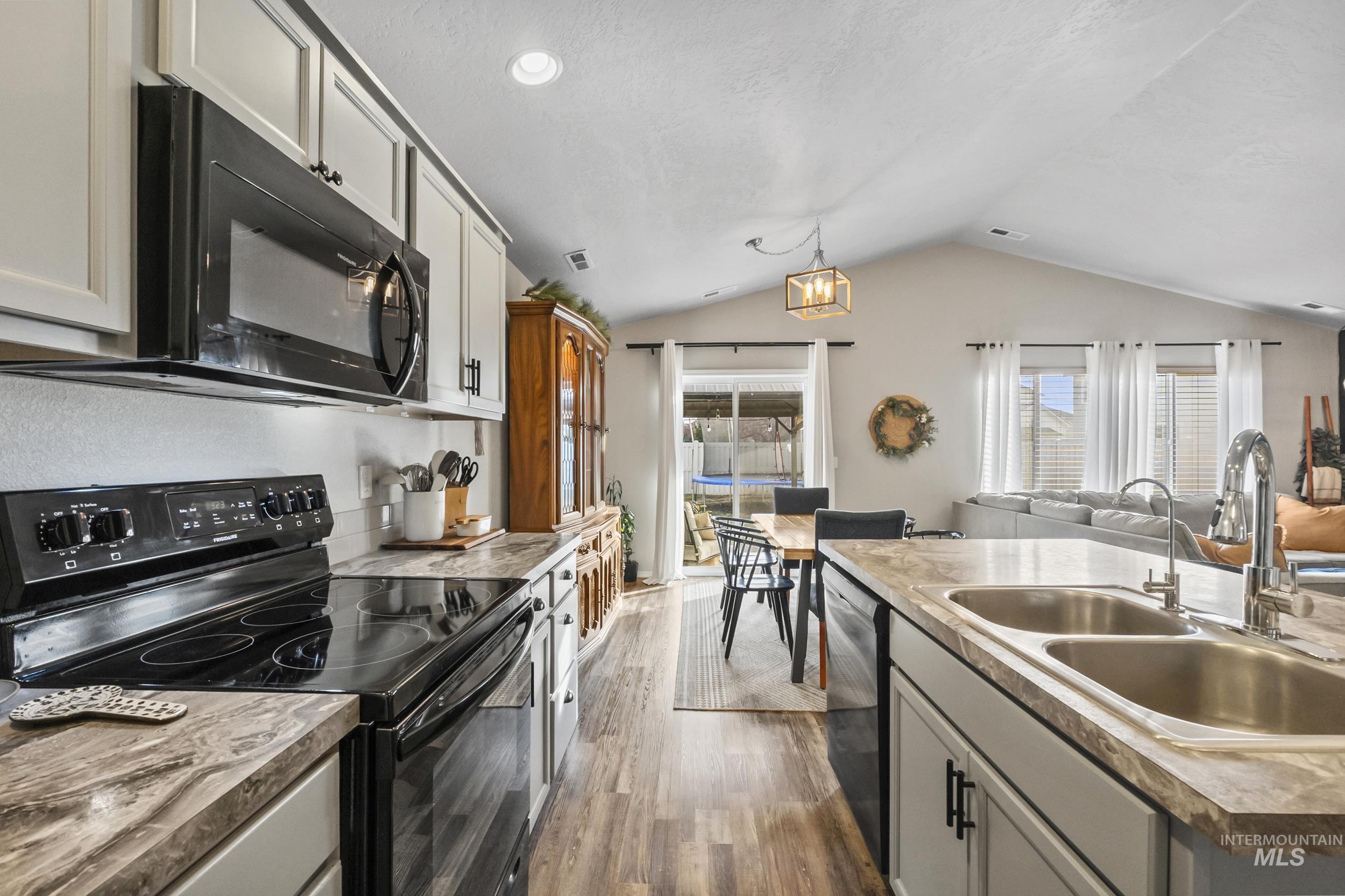 Kitchen featuring black appliances, open floor plan, dark wood-type flooring, decorative light fixtures, and recessed lighting