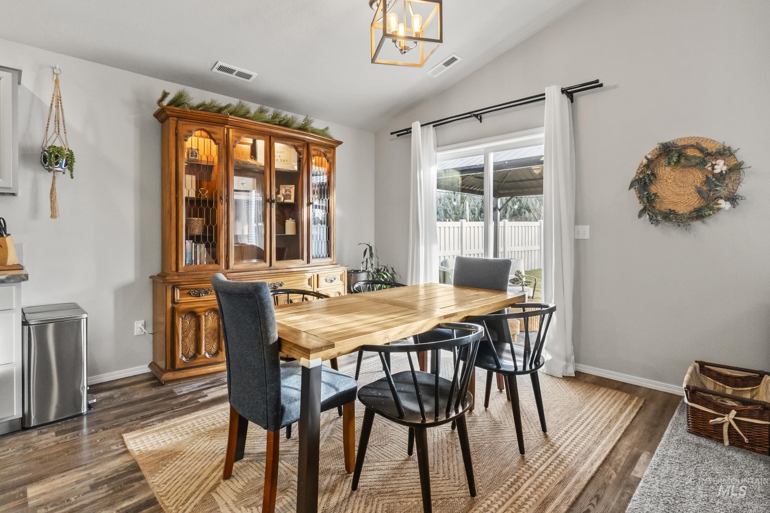Dining room featuring lofted ceiling, dark wood-style floors, and a chandelier