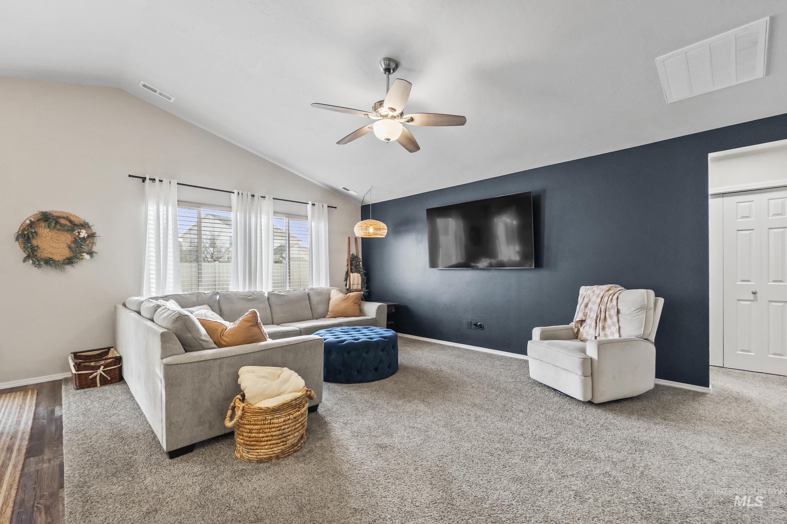 Carpeted living room featuring a ceiling fan and vaulted ceiling