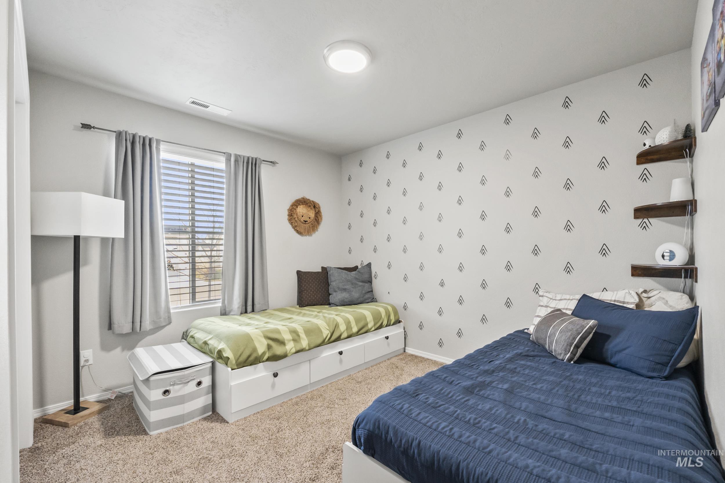 Bedroom featuring wallpapered walls, an accent wall, and carpet
