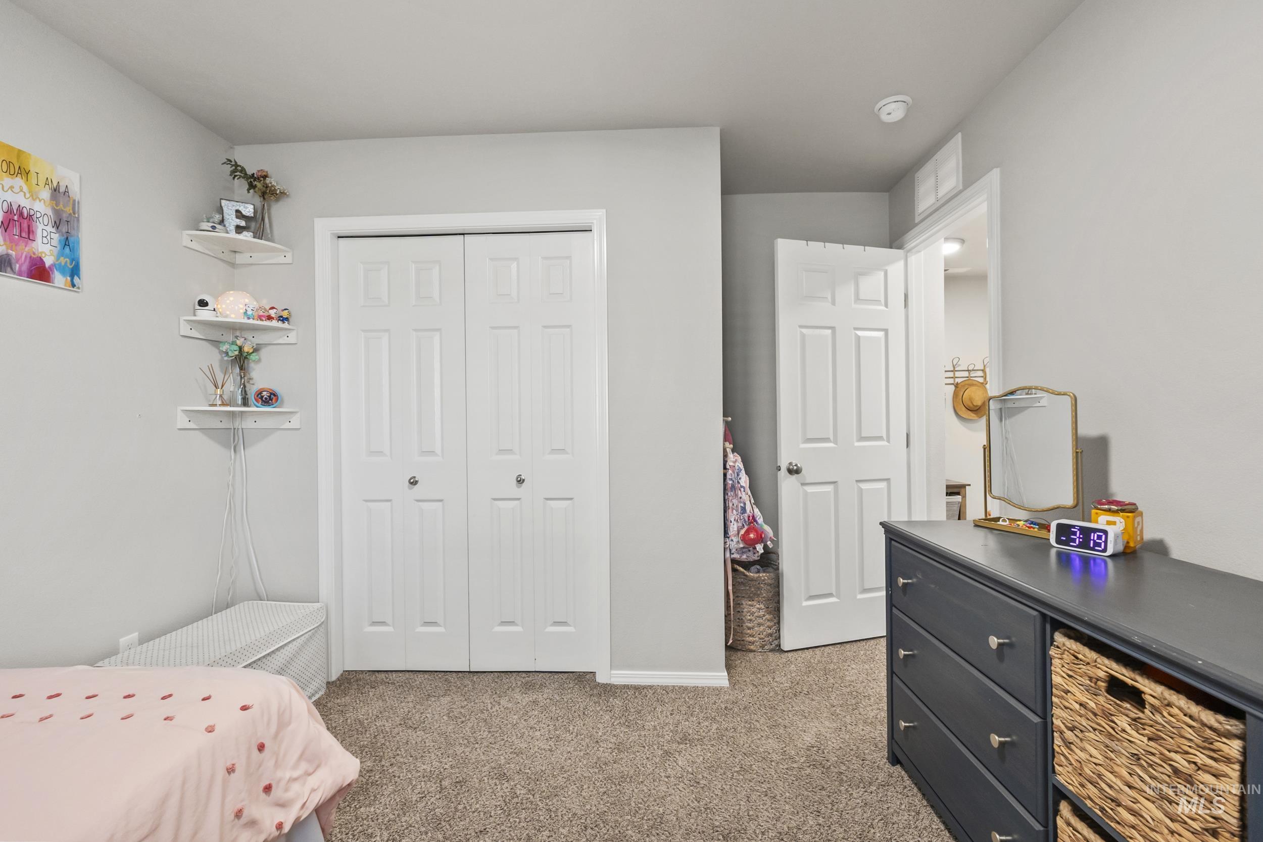 Bedroom with light colored carpet and a closet