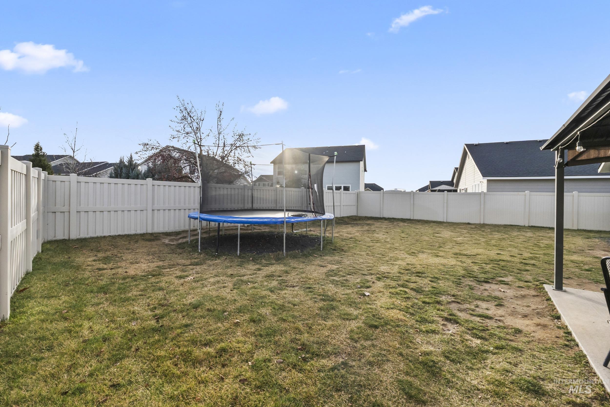 Fenced backyard featuring a trampoline