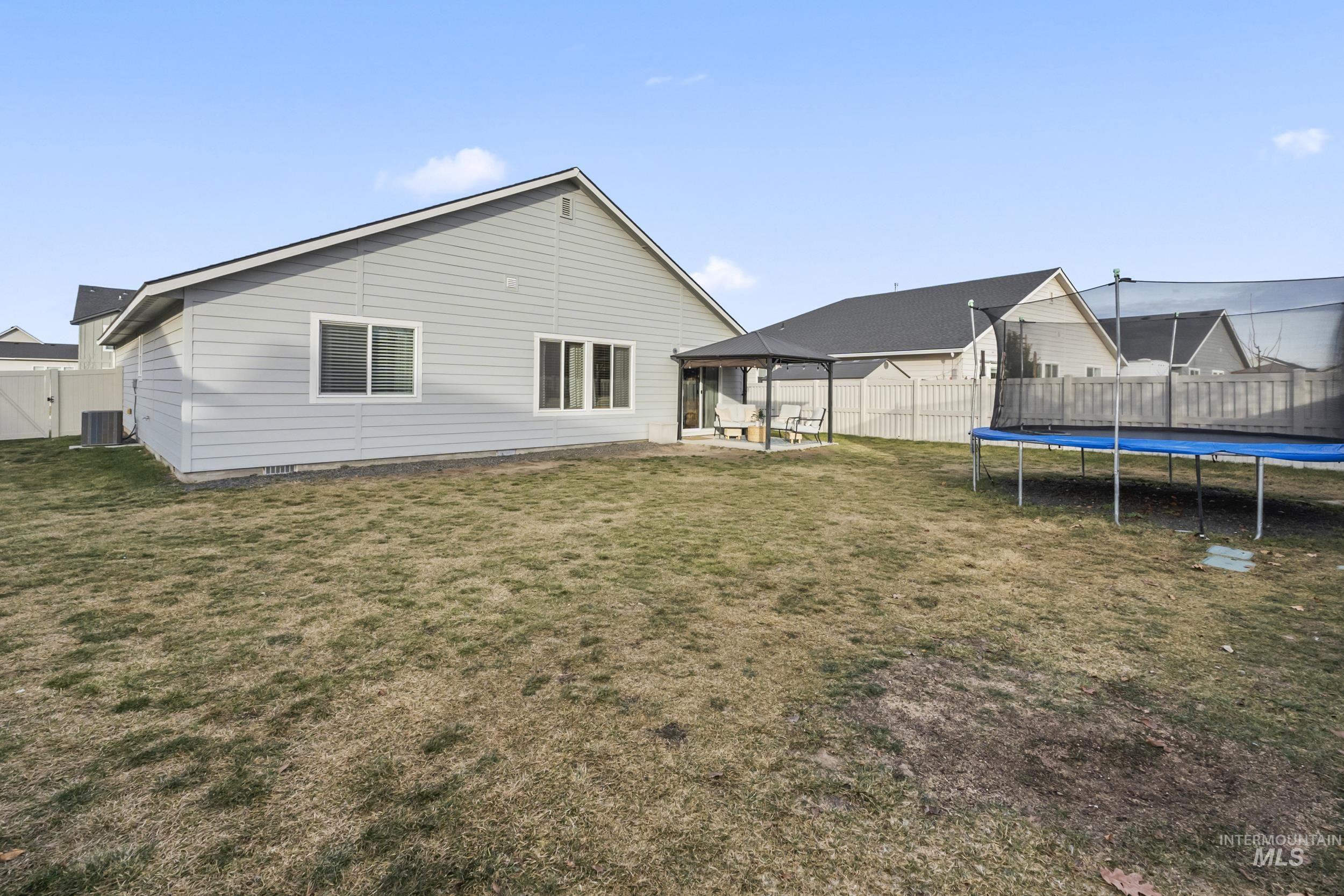 Back of house with a patio area, a trampoline, a fenced backyard, and a gazebo