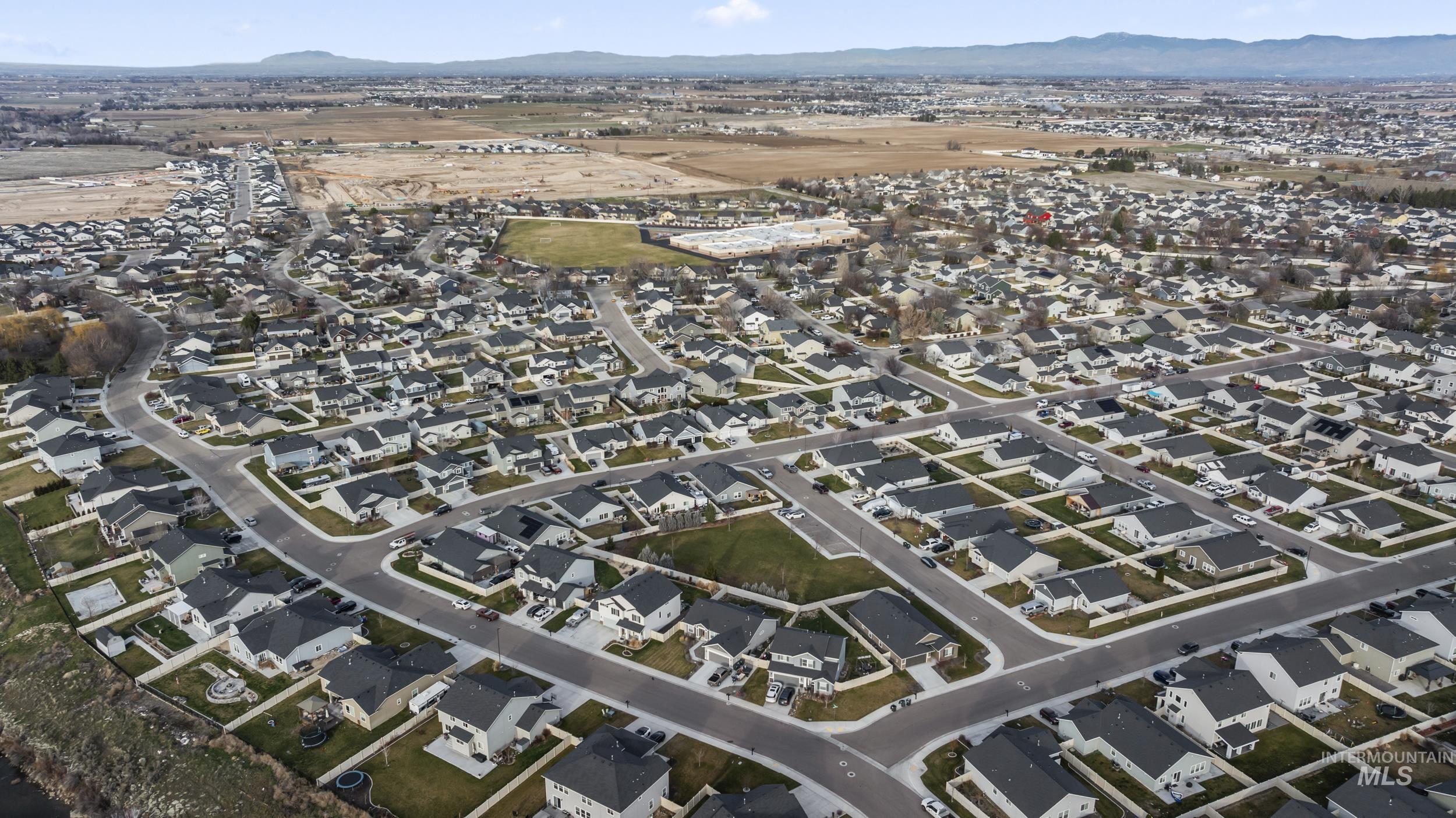 Aerial view of property's location with nearby suburban area and a mountainous background