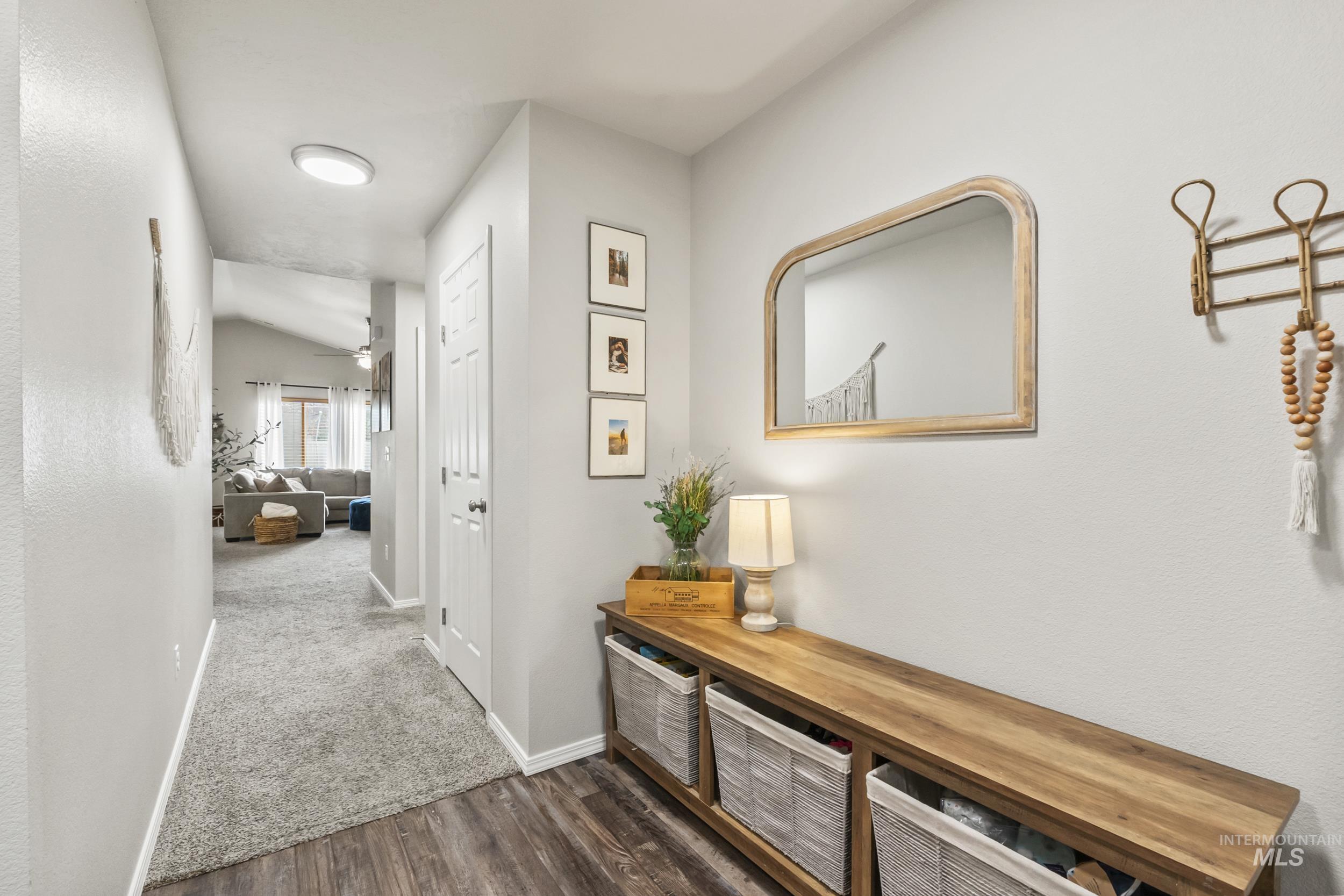 Hallway featuring dark wood-style floors and vaulted ceiling