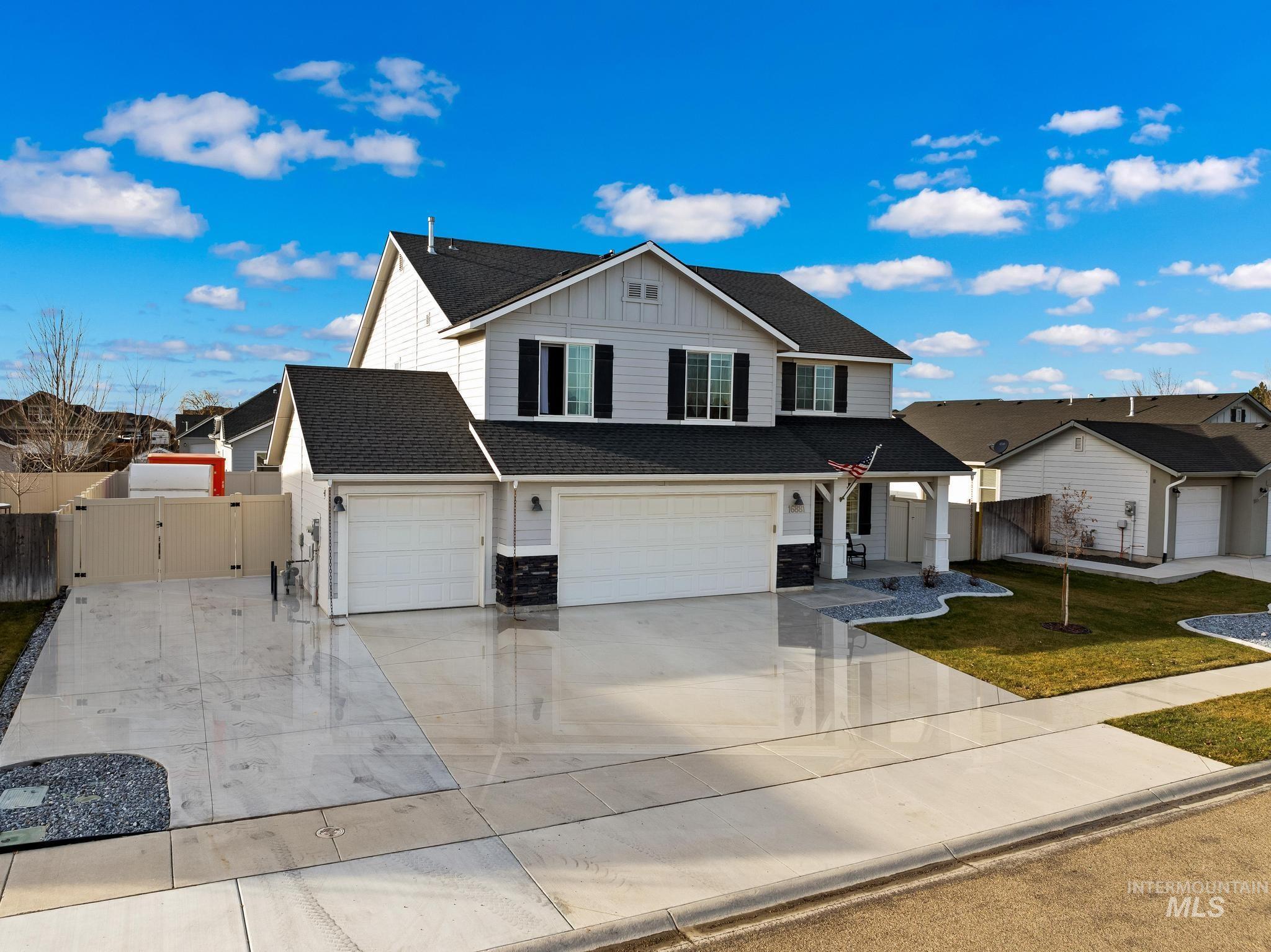 Traditional home with board and batten siding, a shingled roof, a porch, driveway, and a garage