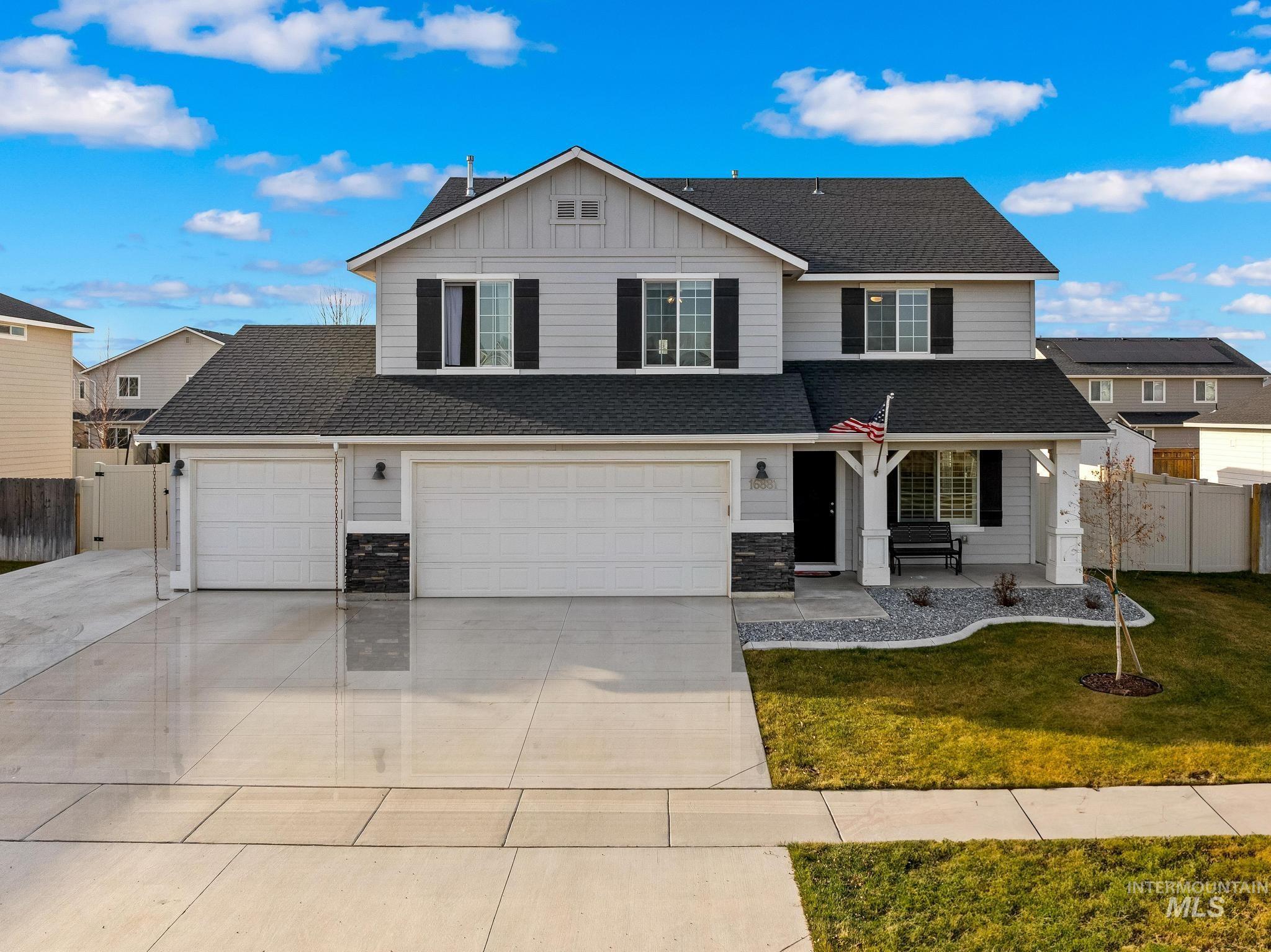 Traditional-style house featuring roof with shingles, a porch, board and batten siding, and driveway