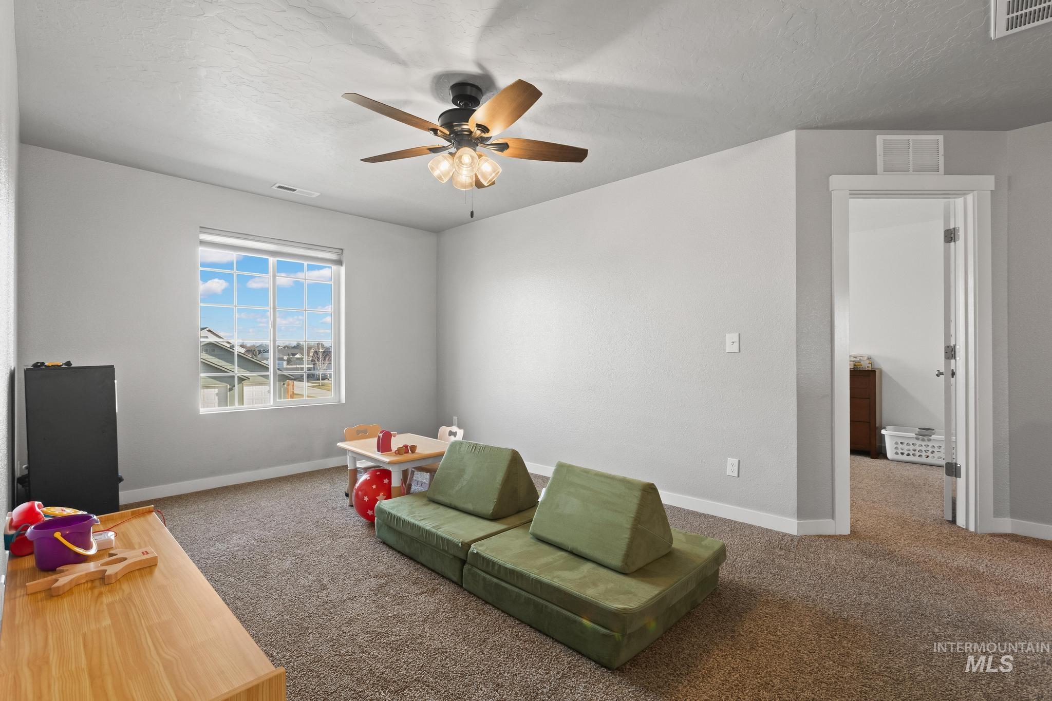 Rec room featuring carpet, a textured ceiling, and ceiling fan