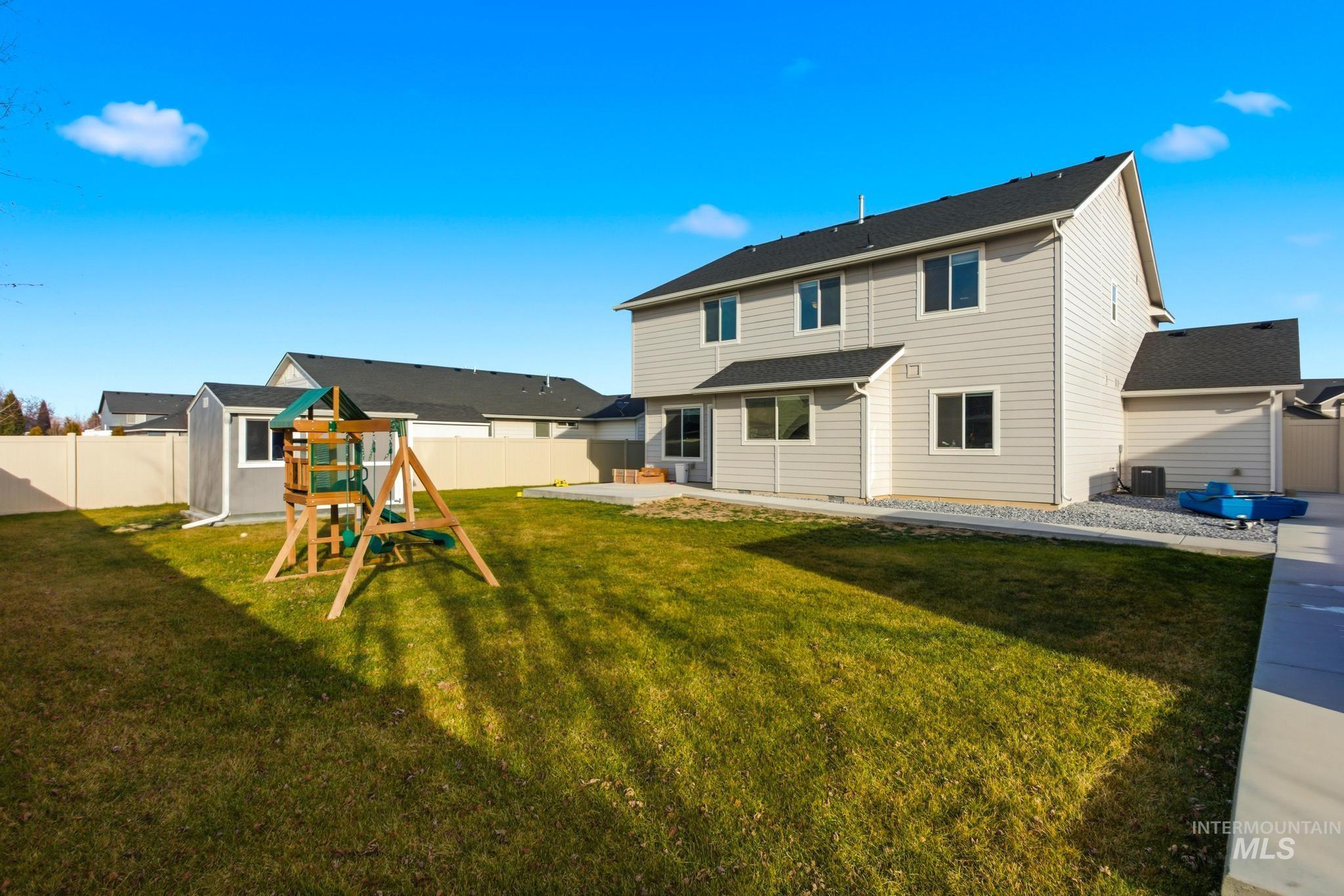 Back of property featuring a playground, a fenced backyard, and a patio