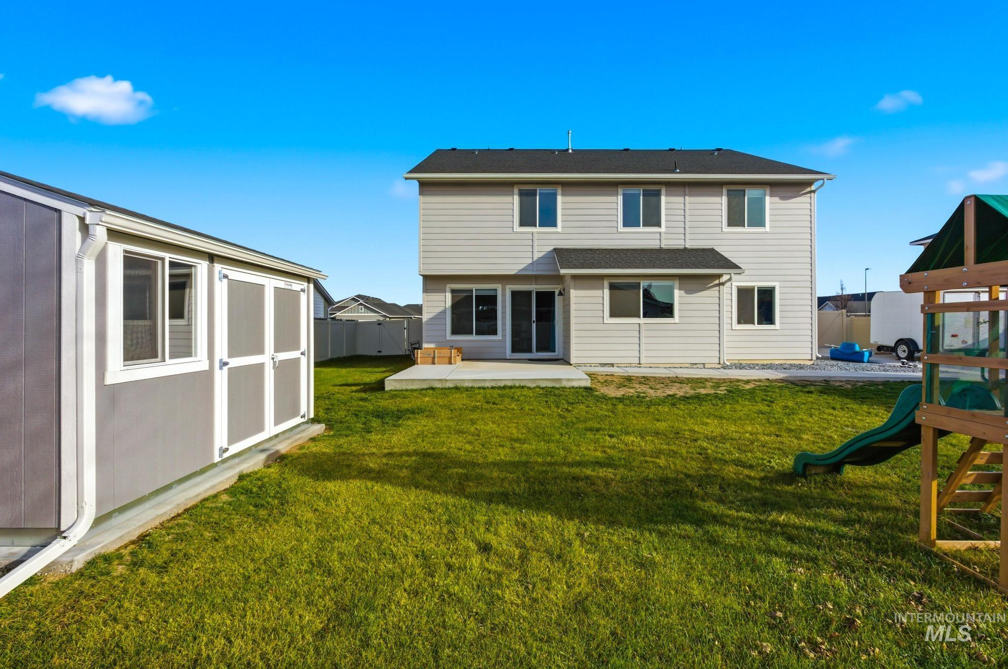 Rear view of property featuring a playground, a shed, and a patio area