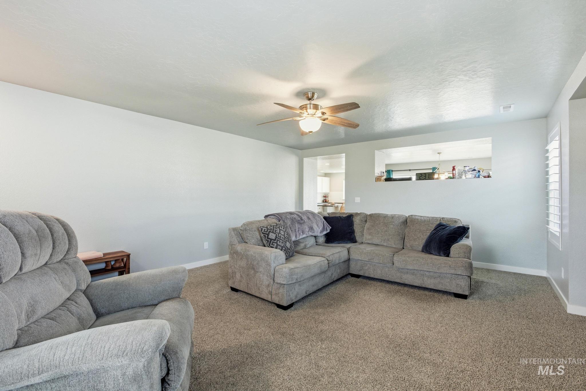 Living room with carpet floors, ceiling fan, and a textured ceiling