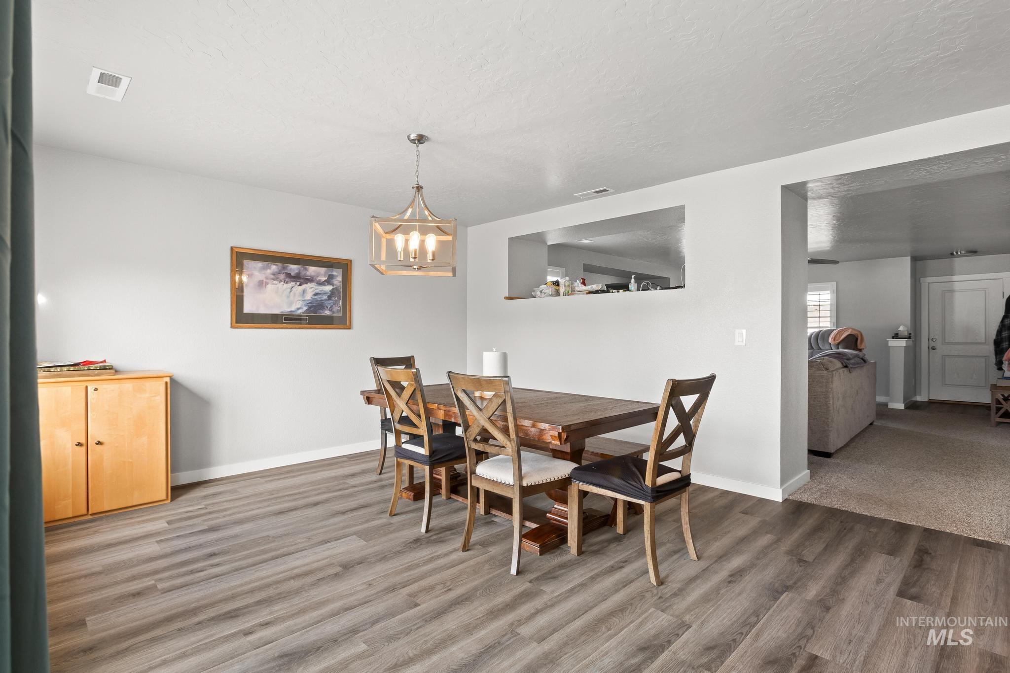 Dining room featuring a textured ceiling, wood finished floors, and a chandelier