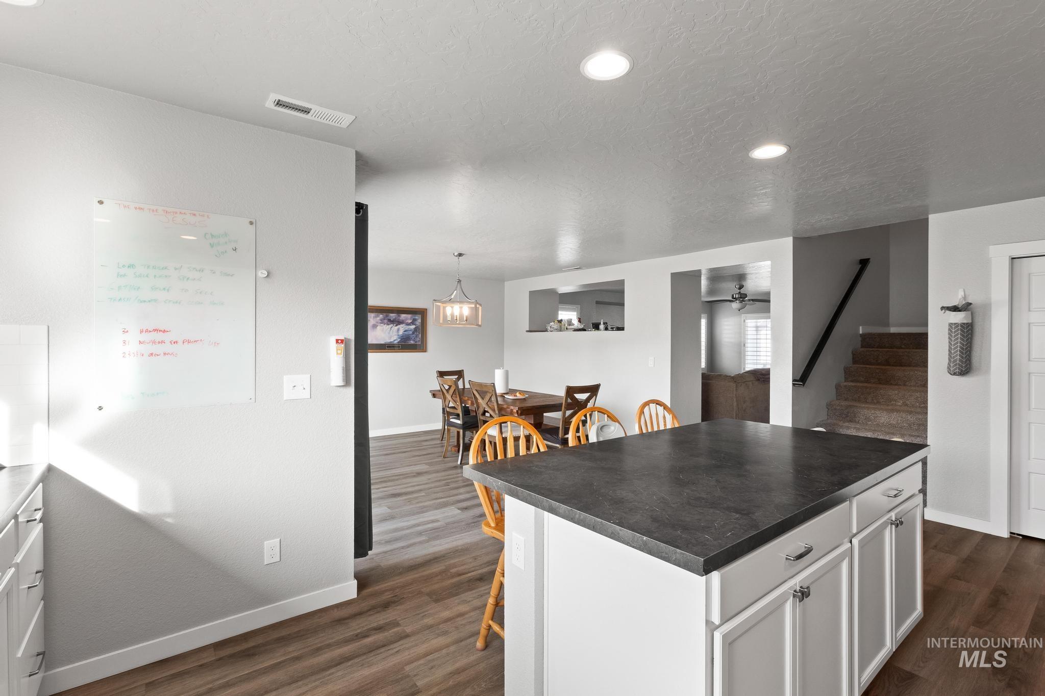 Kitchen with a kitchen breakfast bar, recessed lighting, white cabinetry, a center island, and dark countertops