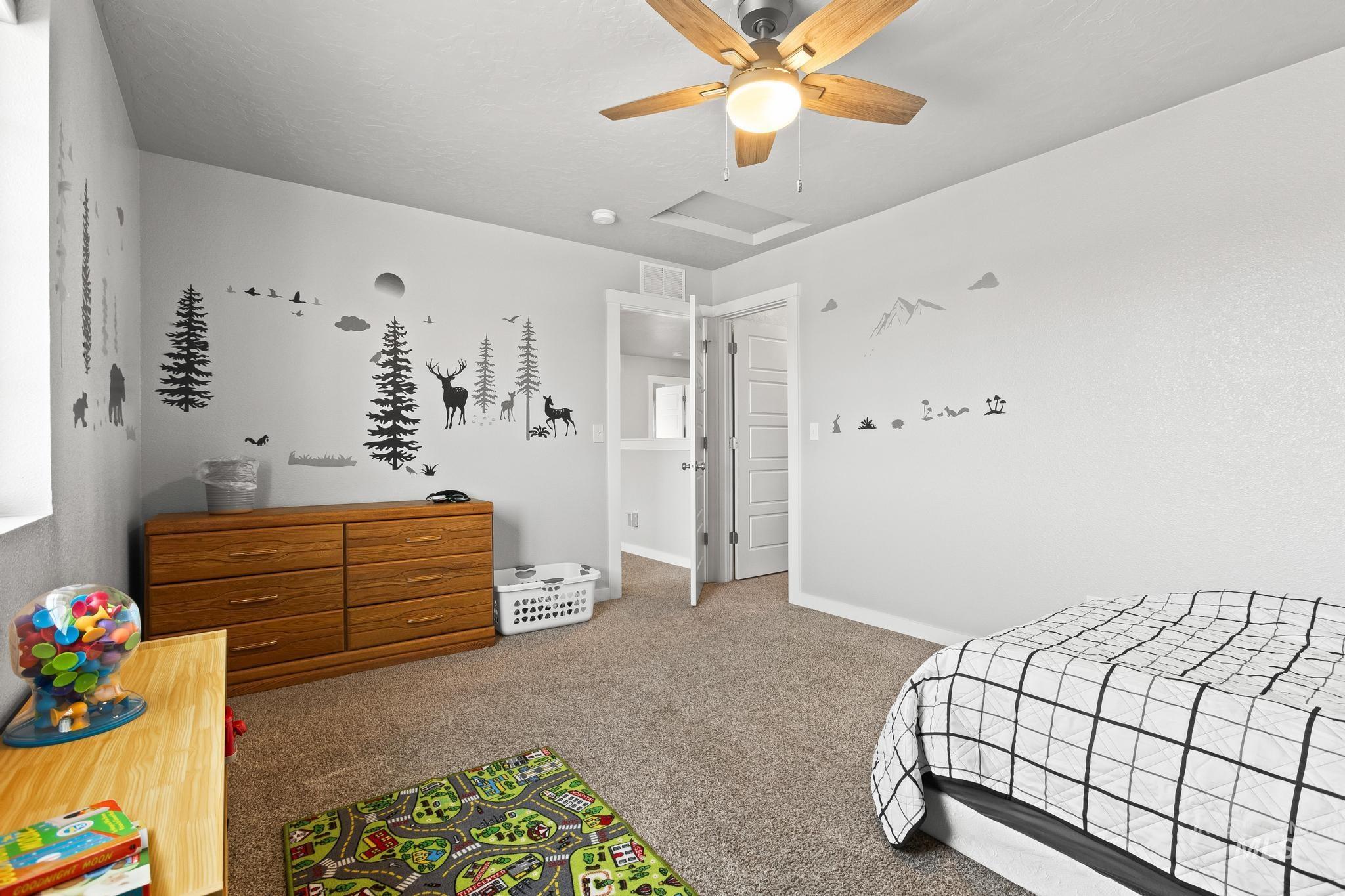 Bedroom with carpet flooring, a ceiling fan, and attic access